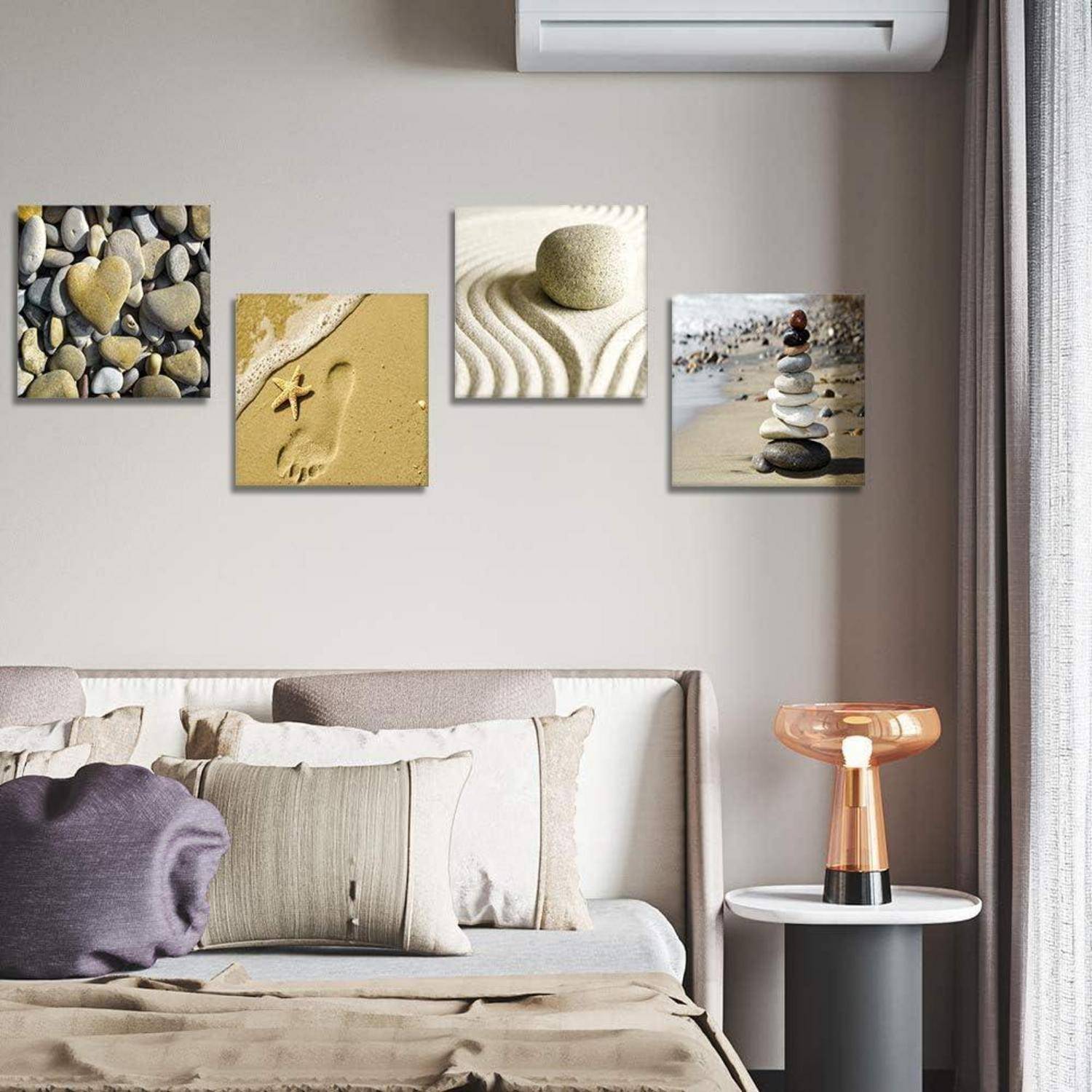 Ein Wohnzimmer mit einem Sofa, Kissen, einem kleinen Beistelltisch, einer modernen Lampe und vier naturthematischen Kunstwerken an der Wand.