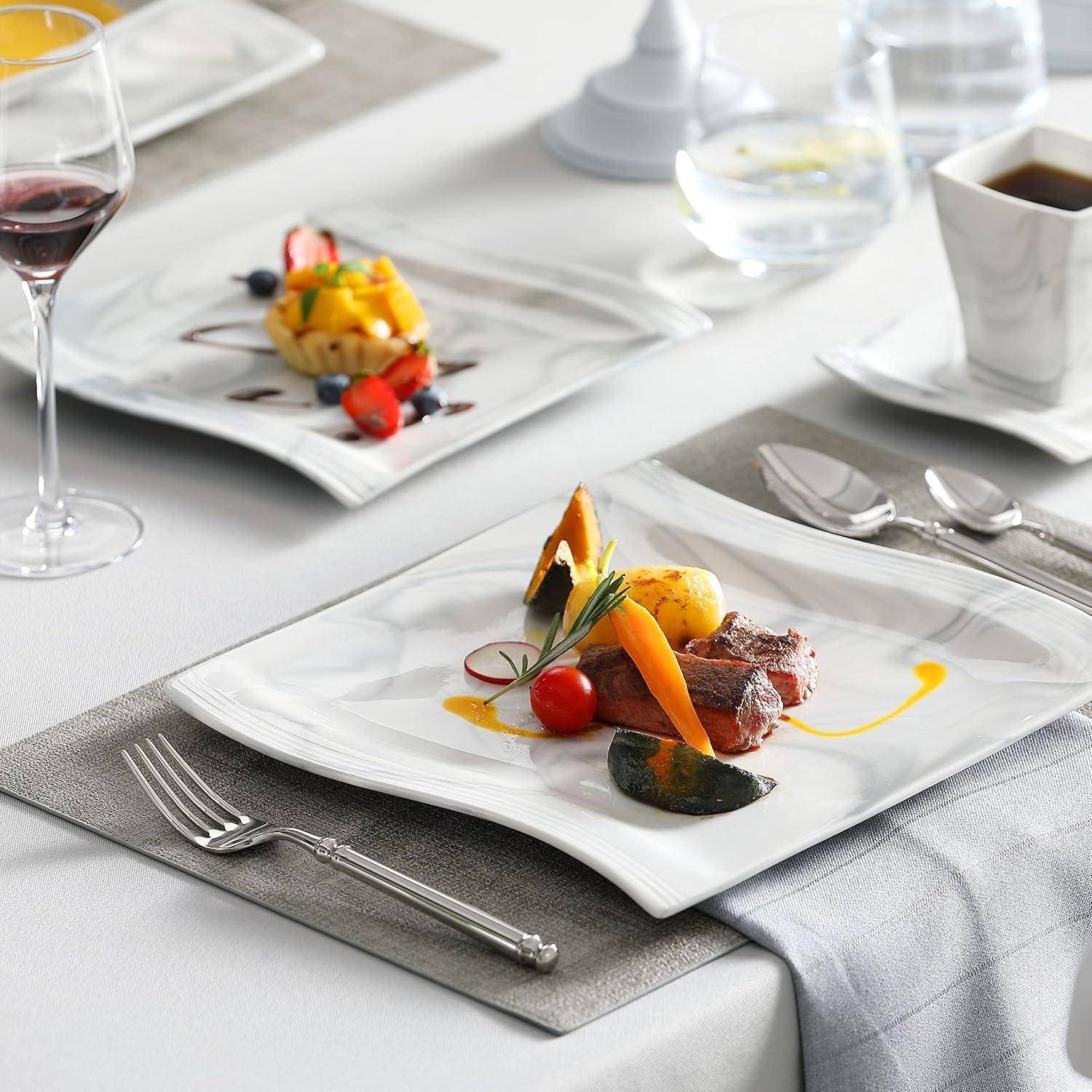 Elegante Tischdekoration mit einer weißen Tischdecke, die ein Gourmet-Gericht mit geschnittenem Rindfleisch, Gemüse und Sauce präsentiert, begleitet von einem Glas Rotwein.