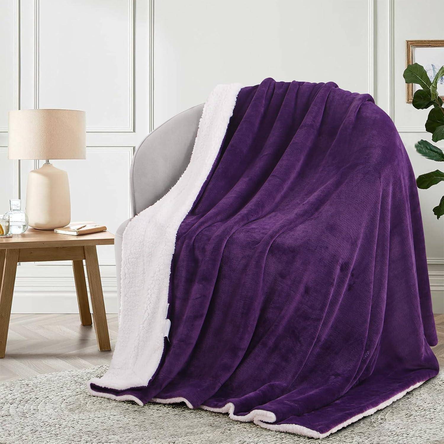 Eine plüschige lila Decke ist über einen weißen Sessel in einem gemütlichen, modernen Raum mit einer Lampe und einem kleinen Tisch in der Nähe gebreitet.