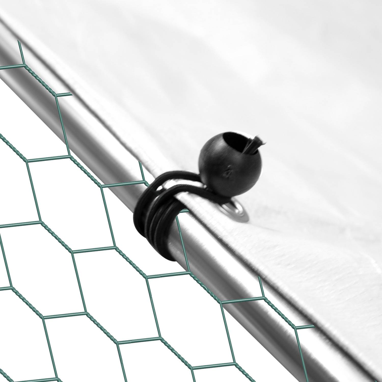 Ein schwarzes Gummikordelbinder befestigt ein weißes Kabel an einem Metallzaun mit sechseckigem Drahtnetzmusters.