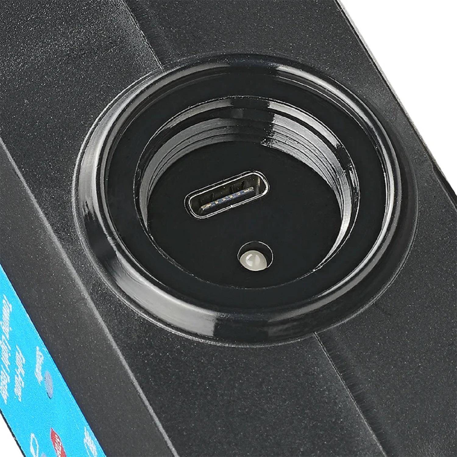 Nahaufnahme eines schwarzen Geräte-Anschlusses mit einer USB-C-Verbindung und einer kleinen LED-Anzeige. Das umgebende Material ist glatt und glänzend.