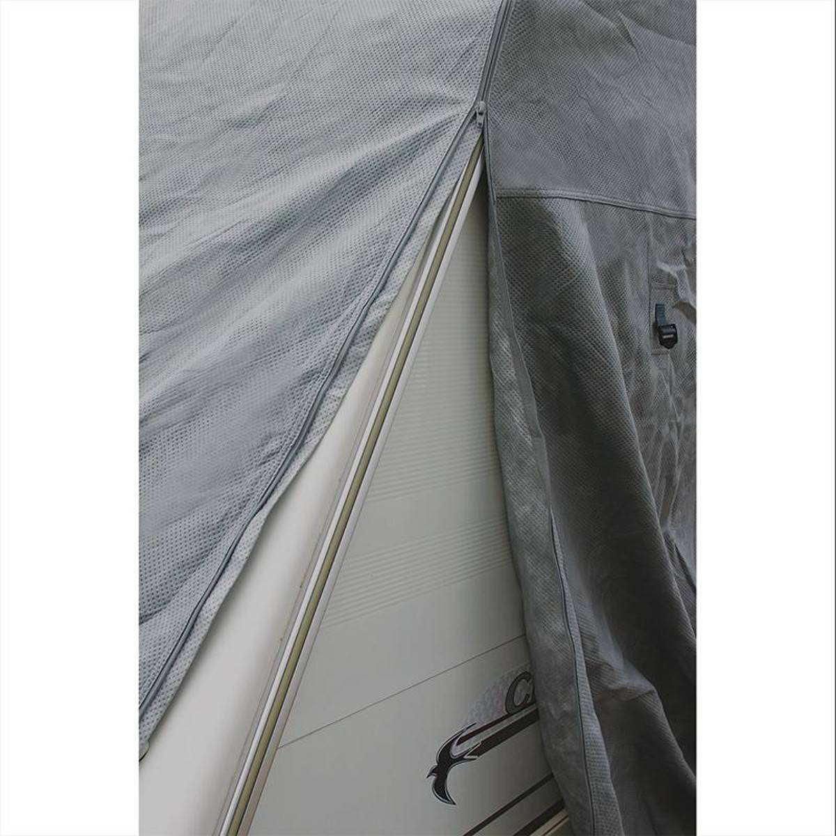 Eine Nahaufnahme einer grauen Plane, die einen Teil eines Fahrzeugs, möglicherweise einen Anhänger, bedeckt, mit einem sichtbaren Ziermotiv an seiner Seite.