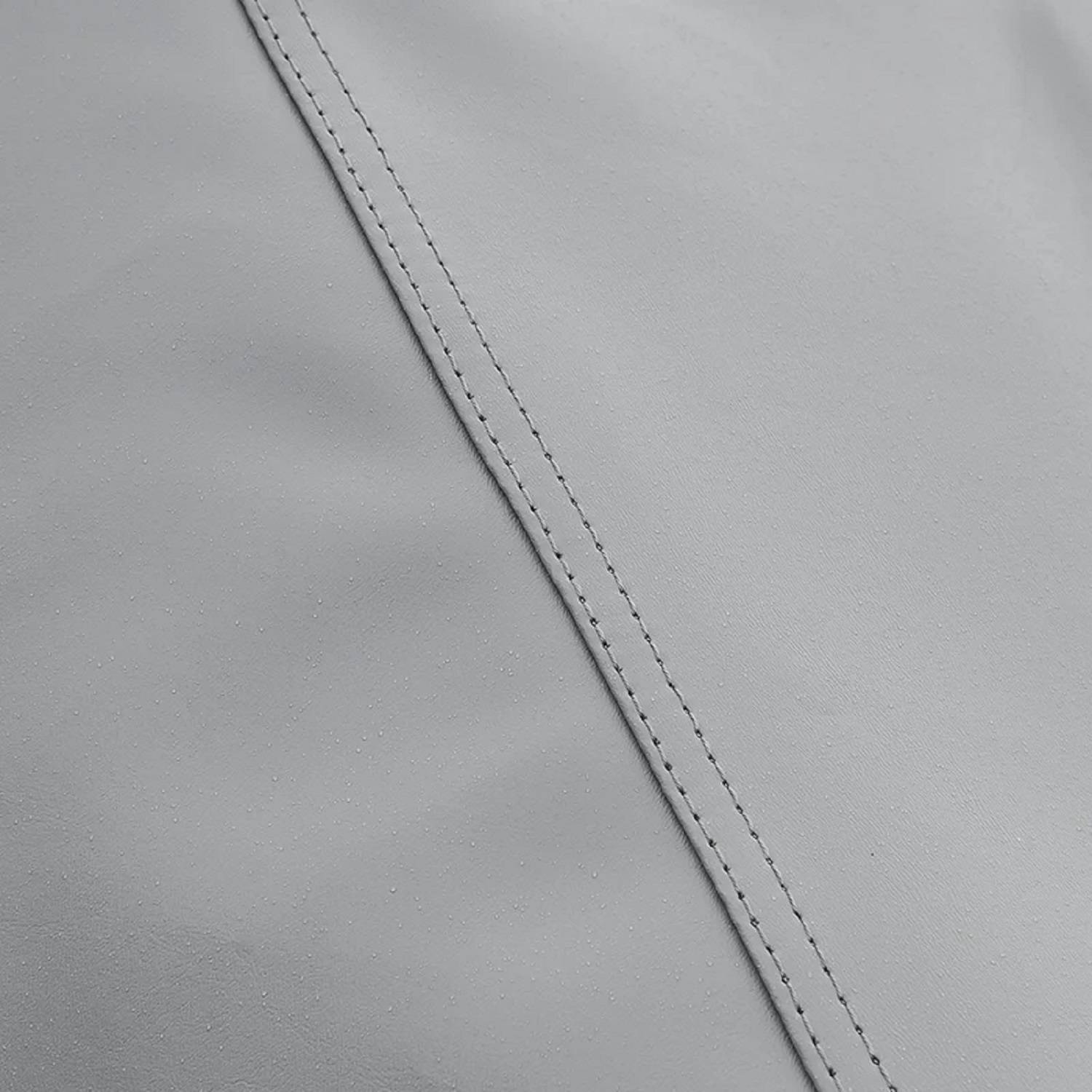 Nahaufnahme von grauem Lederstoff mit sichtbaren Nähten, die Textur und Qualität zeigen.