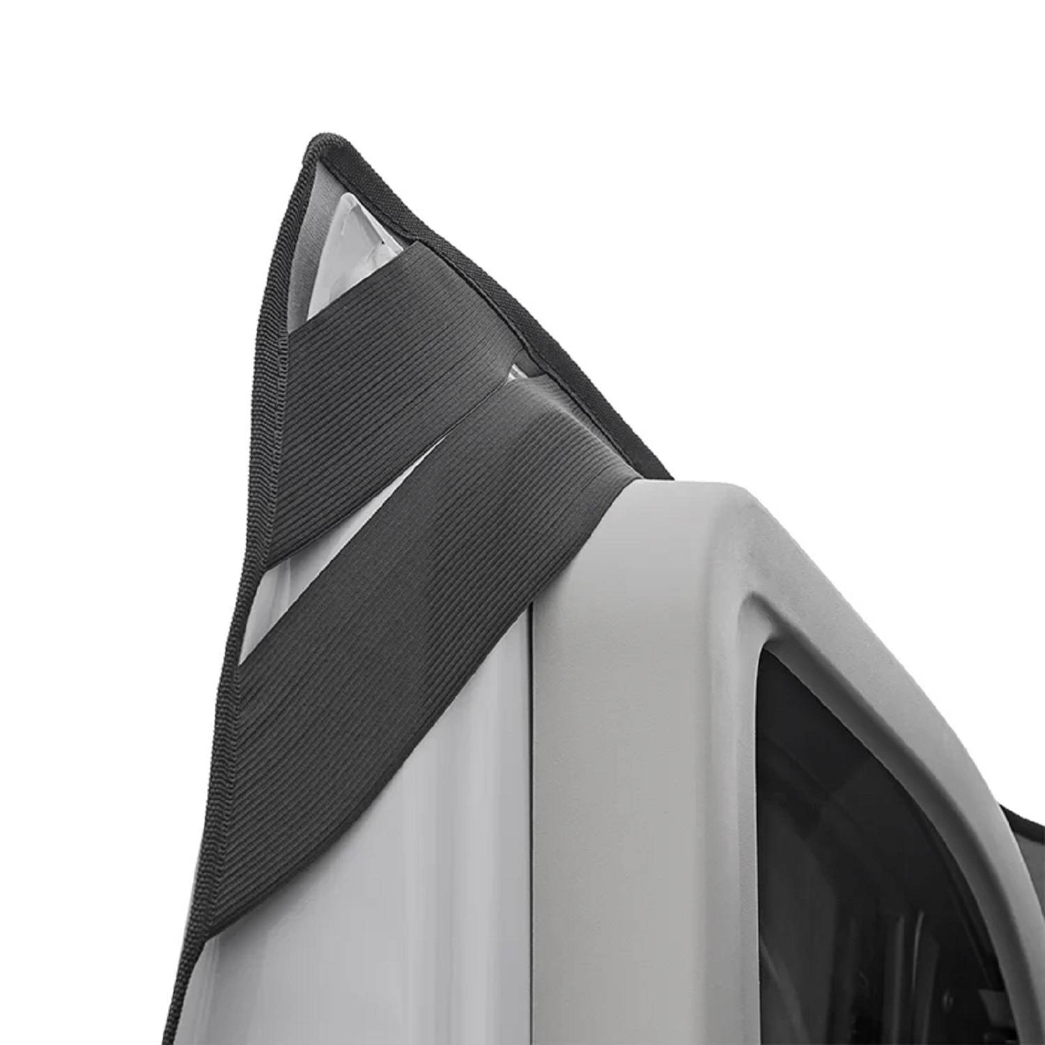 Eine Nahaufnahme eines Außenspiegels eines Fahrzeugs mit einem Stoffwindabweiser, der an der Kante des Spiegels und am Fensterrahmen zu sehen ist.