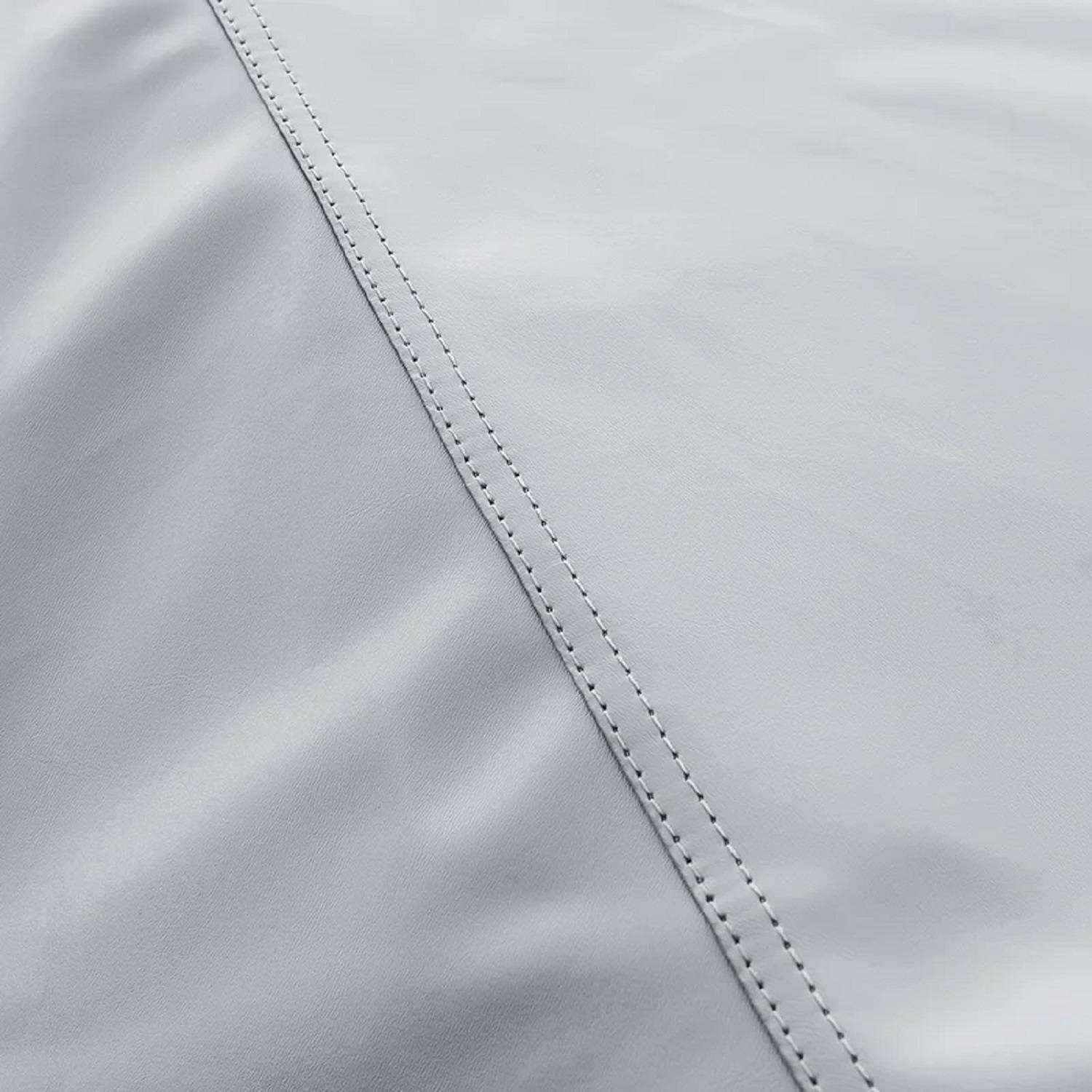 Nahaufnahme von glattem, hellgrauem Stoff mit sichtbaren Nähten, die Textur und Details zeigt.