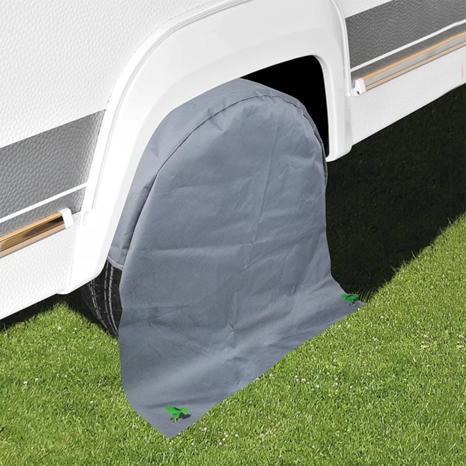 Das Bild zeigt eine graue Abdeckung, die das Rad eines geparkten weißen Wohnmobils schützt, höchstwahrscheinlich um Schäden durch Sonne und Wetter zu verhindern.