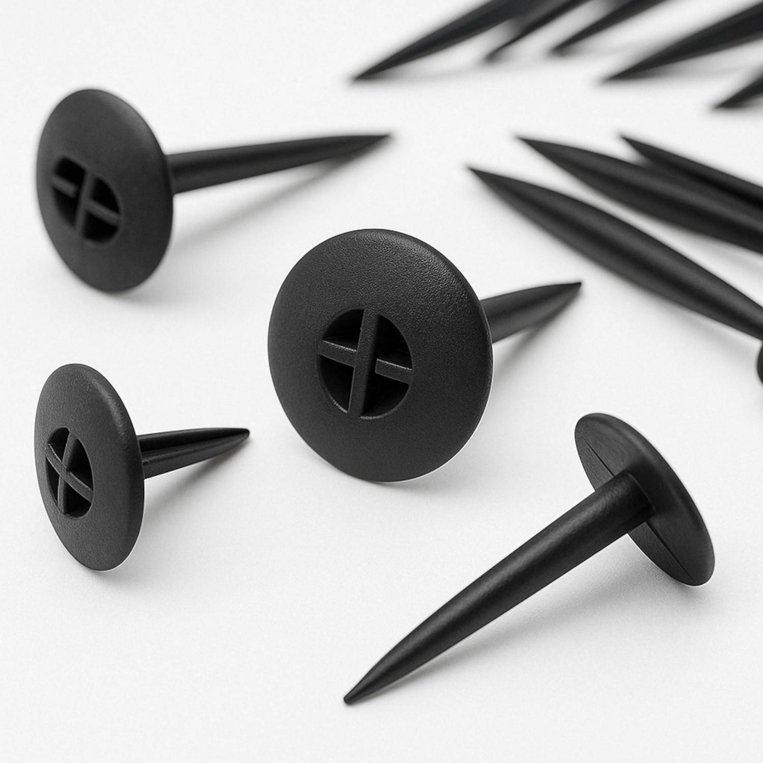 Eine Reihe von schwarzen Kunststoff-Gartenpflöcken in unterschiedlichen Größen, auf weißem Hintergrund ausgelegt, mit glatten, runden Köpfen und kreuzförmigen Rillen.