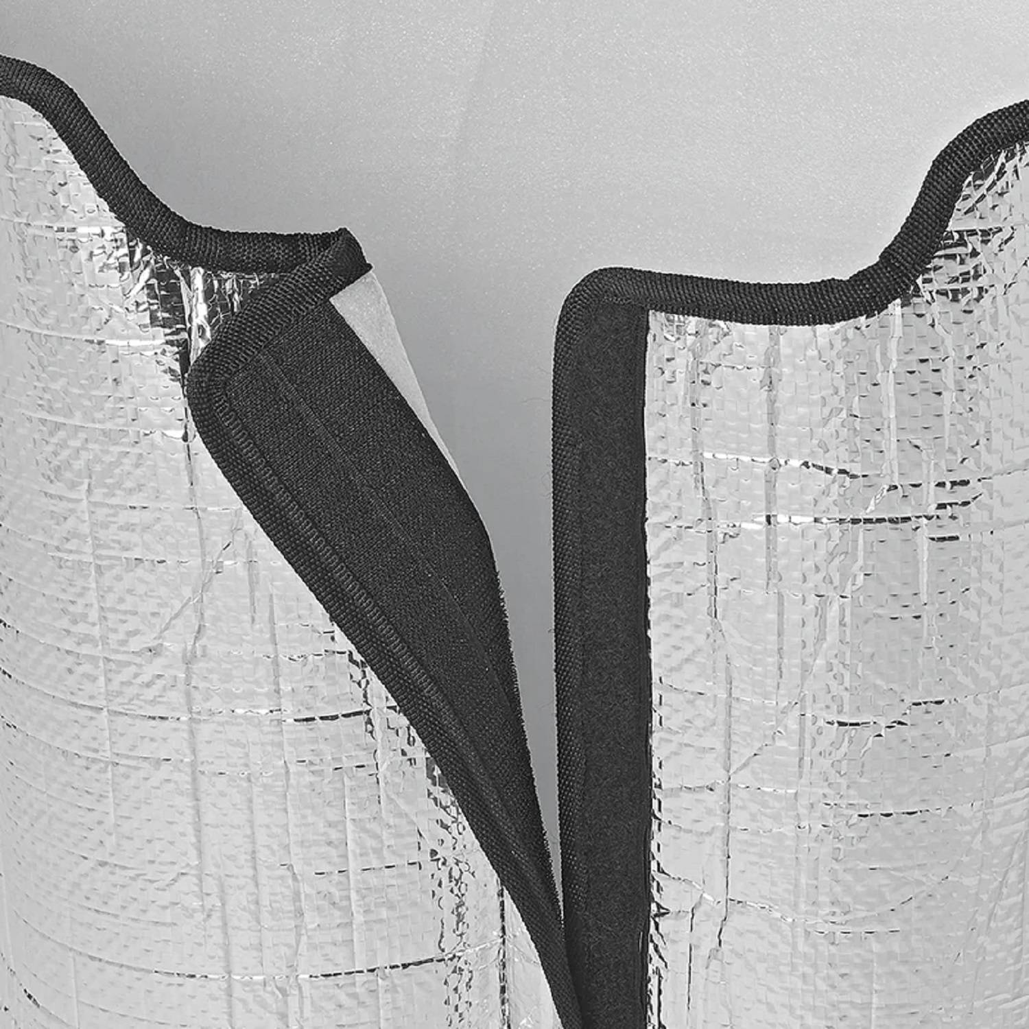 Nahaufnahme eines silbernen reflektierenden Isolationsmaterials mit schwarzen Kanten, die Textur und gefaltetes Design zeigen.