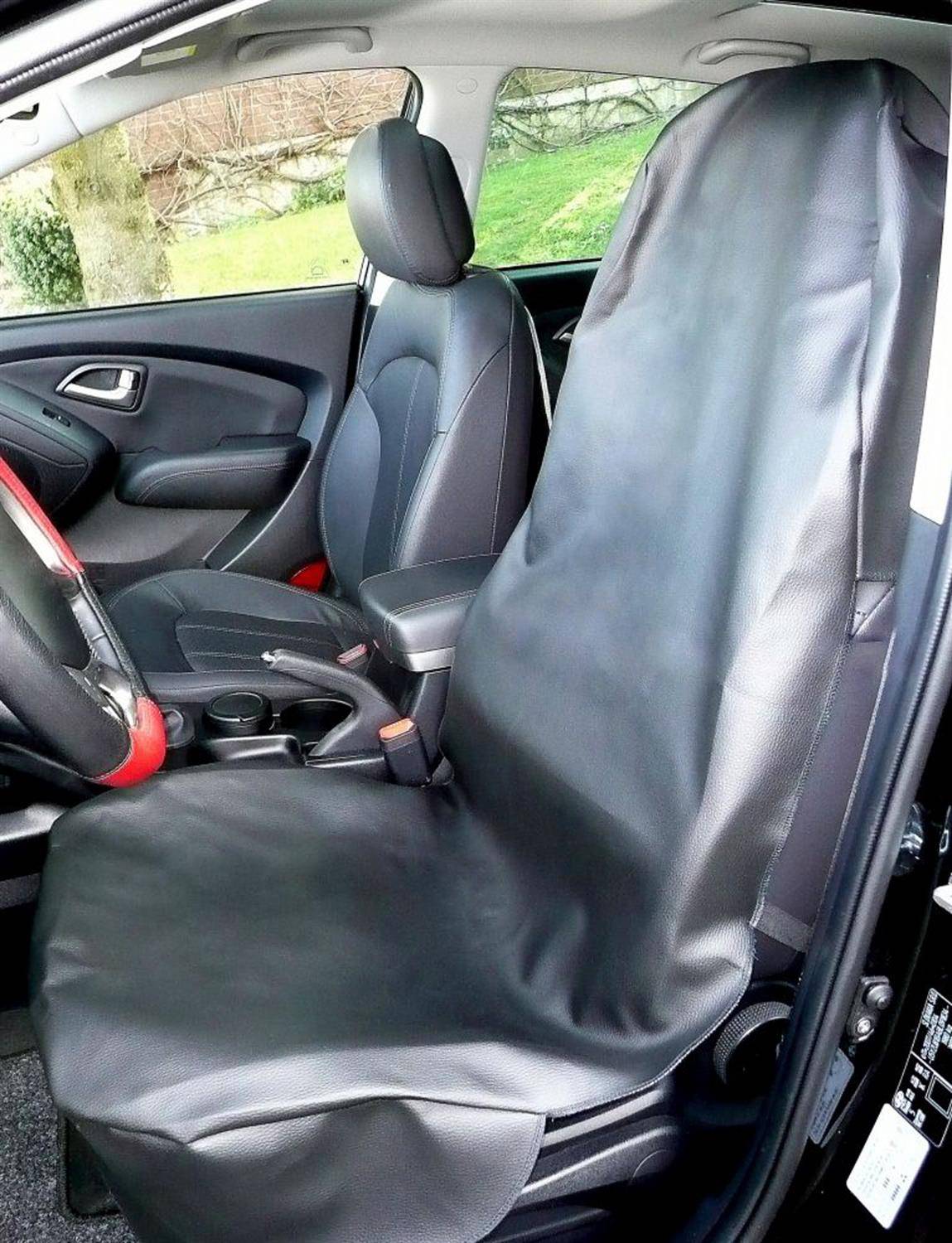 Das Foto zeigt das Wageninnere mit einer großen Ledersitzbezug, der den Fahrersitz schützt. Das Armaturenbrett und das Lenkrad sind teilweise zu sehen.