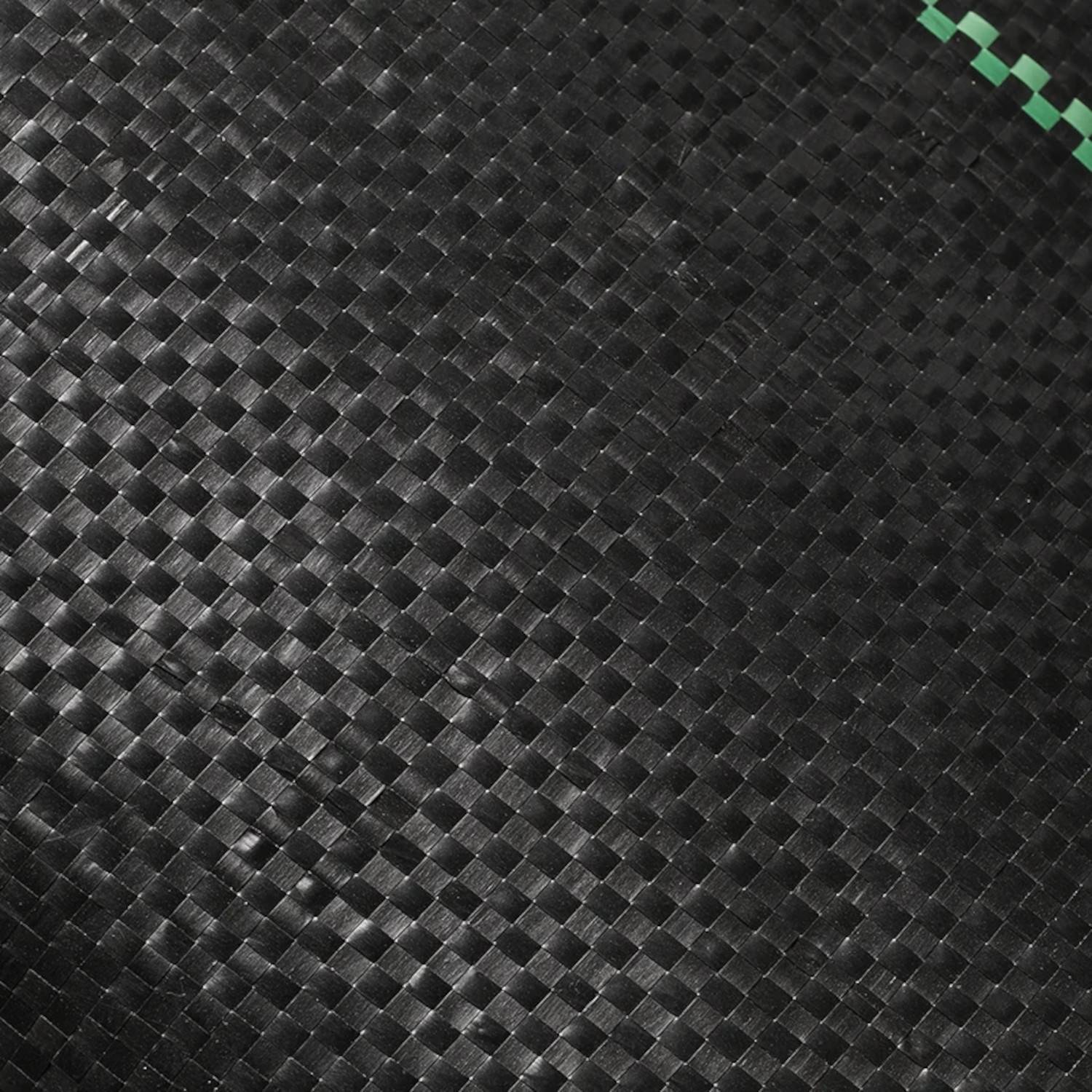 Eine Nahaufnahme von schwarzem gewebtem Maschenstoff mit einer grünen Linie, die diagonal über die obere rechte Ecke verläuft.