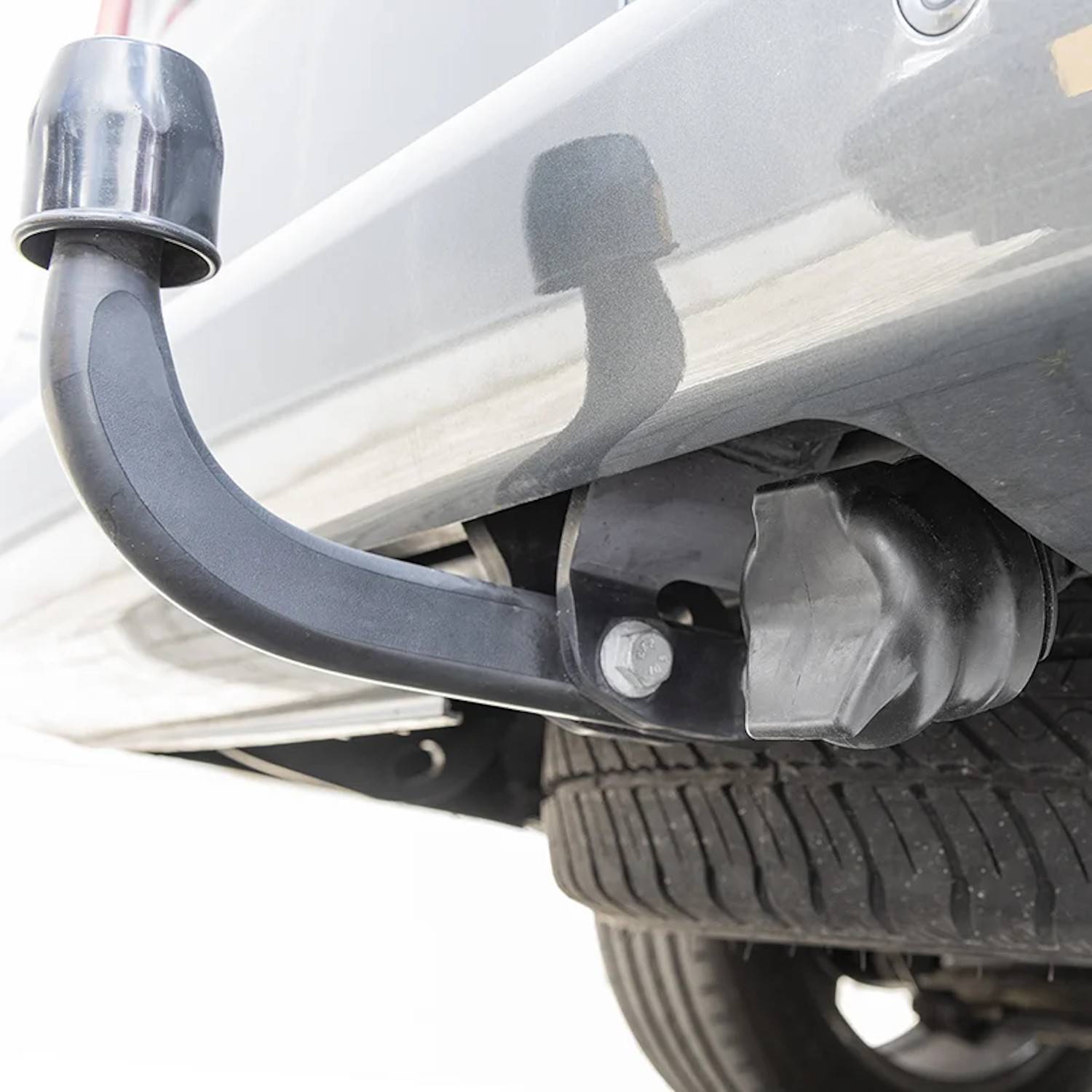 Eine Nahaufnahme einer Abschleppvorrichtung an der Rückseite eines Fahrzeugs mit einer Anhängerkupplung, die am Fahrzeugrahmen nahe dem hinteren Reifen befestigt ist.