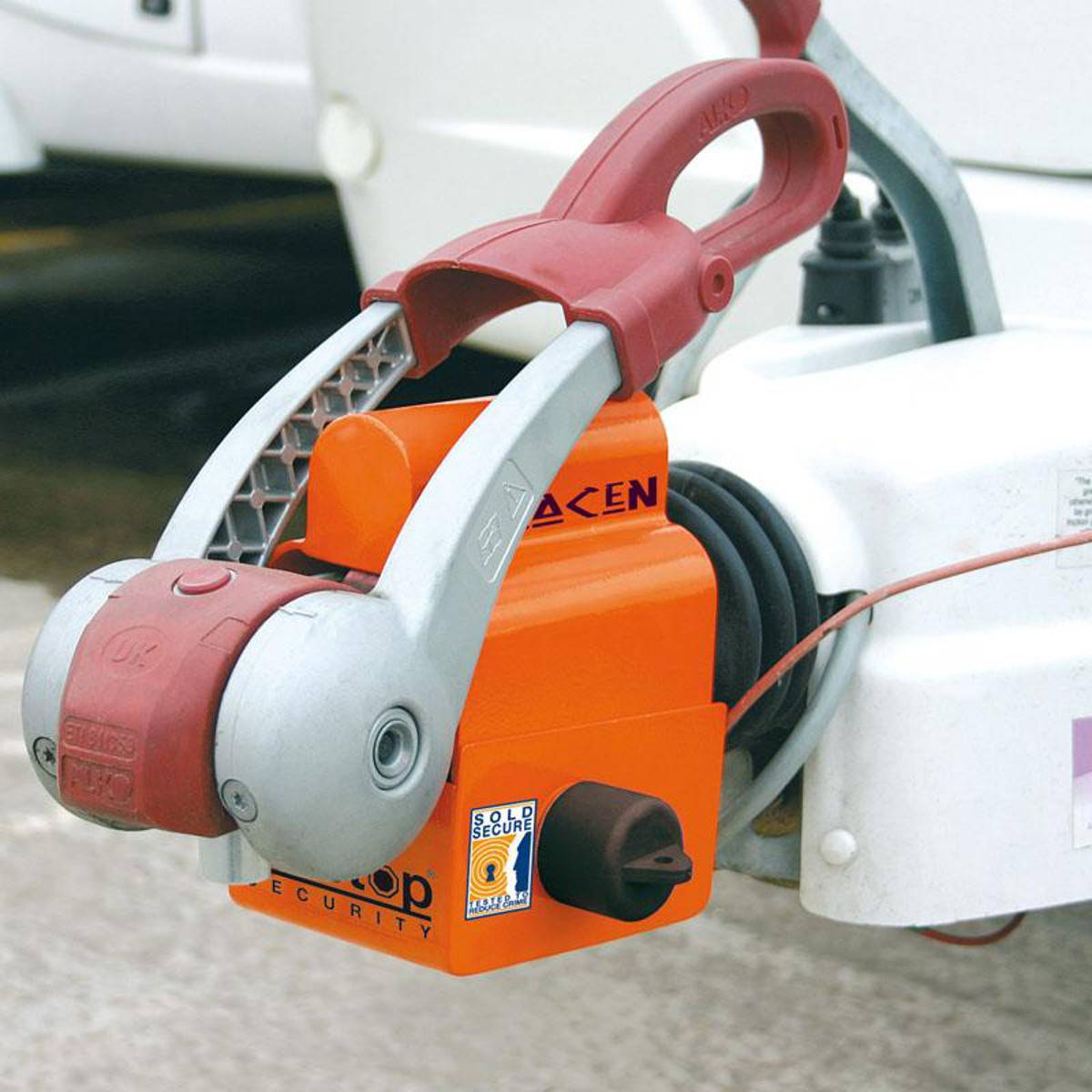 Eine Lenkradsperre in einem Parkplatzbereich, mit einem rot-silbernen Sperrmechanismus, die die Fahrzeugsicherheit gewährleistet.