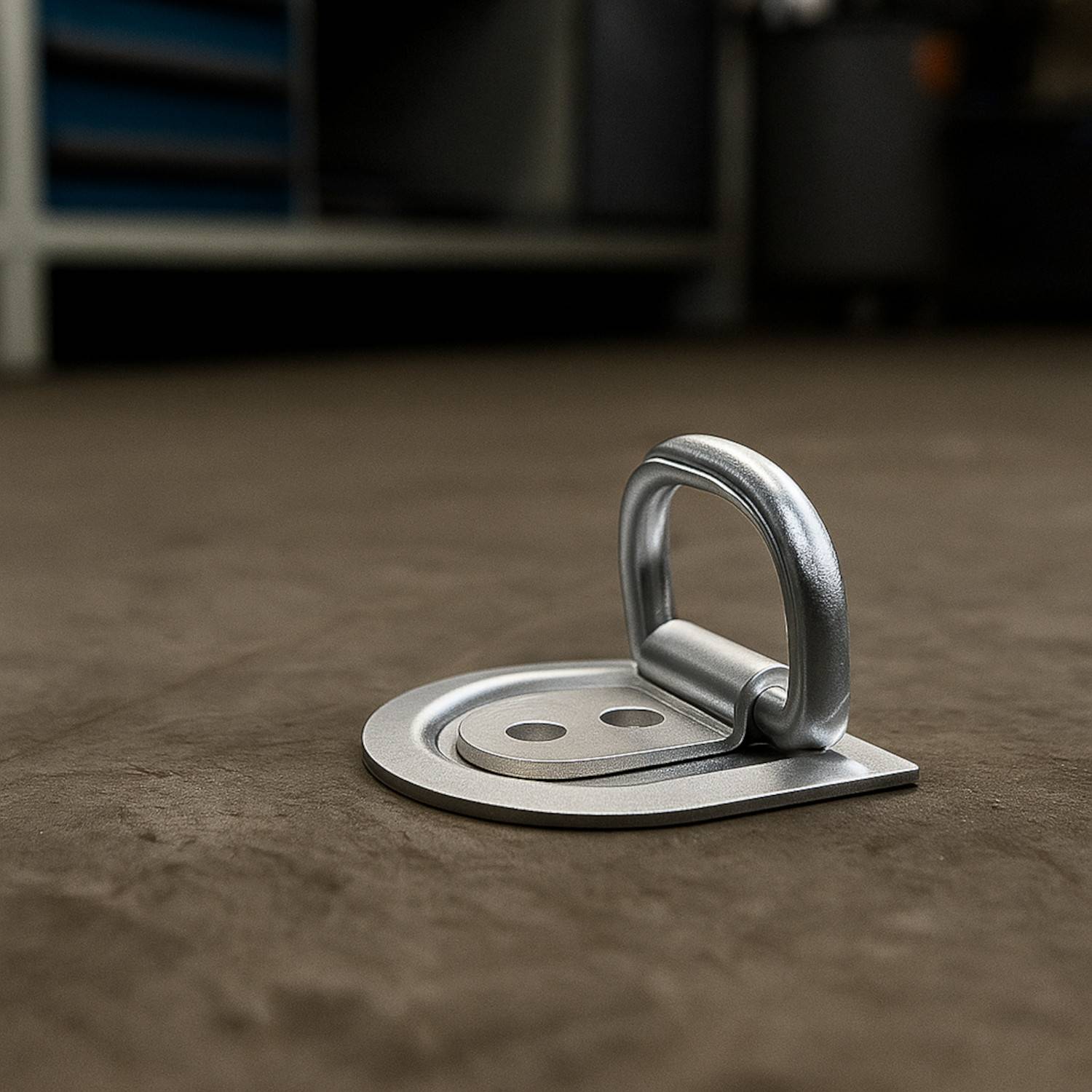 Ein Metall-Bodenankerpunkt wird auf einem Betonboden in einer Werkstattumgebung installiert und dient zum sicheren Befestigen von Ausrüstung oder Materialien.