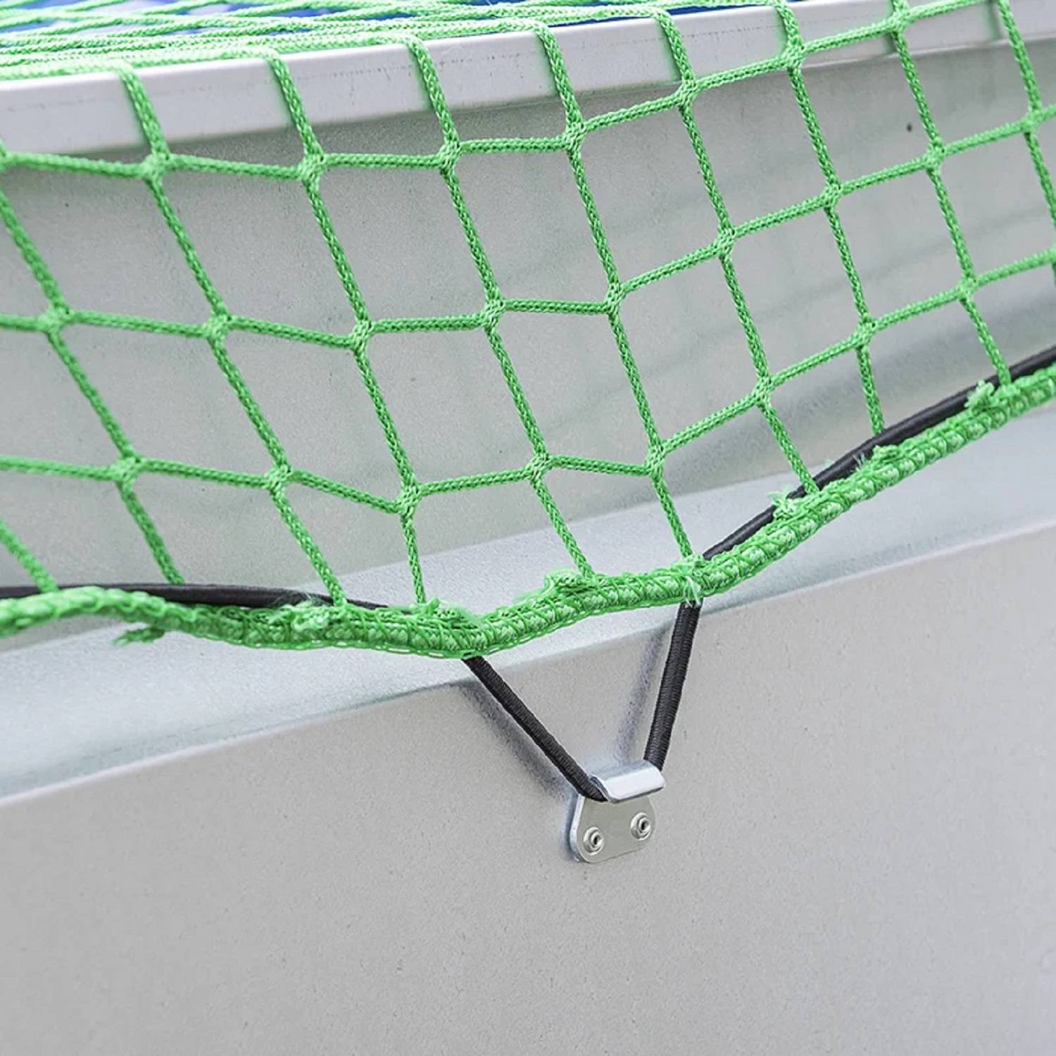 Ein Nahaufnahmefoto eines grünen Netzes, das mit einer schwarzen Spanngummi an einem Metallrahmen befestigt ist und höchstwahrscheinlich für Sicherheits- oder Lagerzwecke verwendet wird.