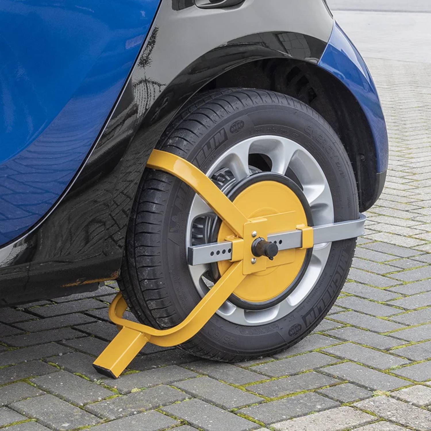 Ein Auto steht auf einer asphaltierten Oberfläche mit einer gelben Radkralle, die am Hinterrad angebracht ist und eine Bewegungsunfähigkeit anzeigt.