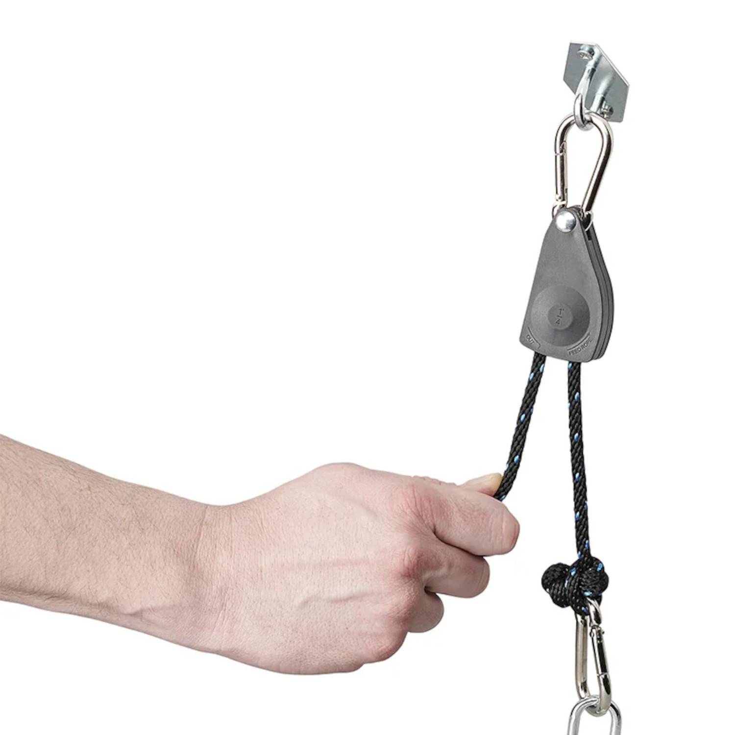 Eine Hand, die ein schwarzes Seil hält, das an einem manuellen Flaschenzugsystem mit einem Metallhaken befestigt ist und das Anheben oder die Spannungseinstellung veranschaulicht.