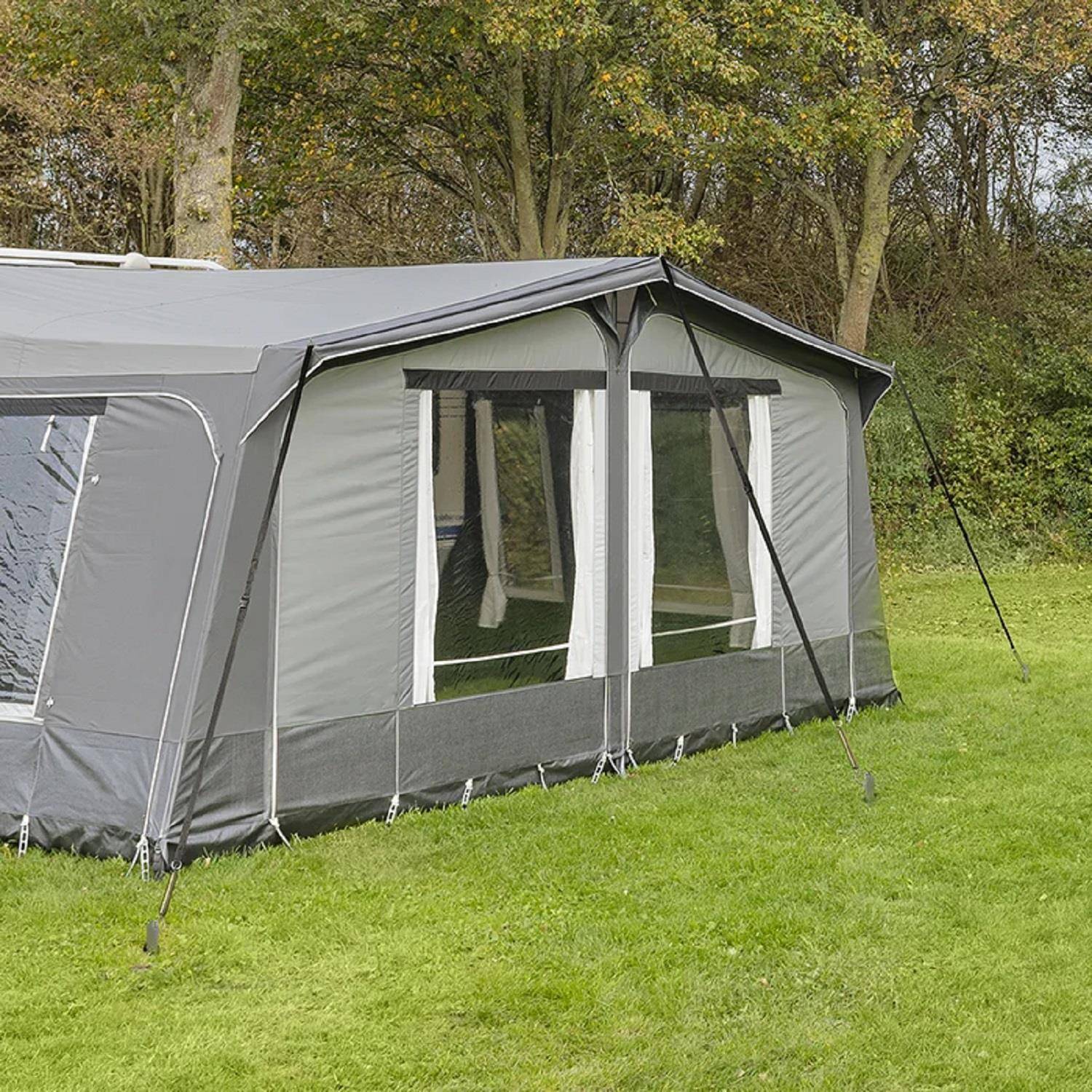 Ein großes graues und weißes Zelt, das auf einem grasigen Boden aufgestellt wurde, mit Bäumen im Hintergrund, was eine Campingszene in der Natur andeutet.