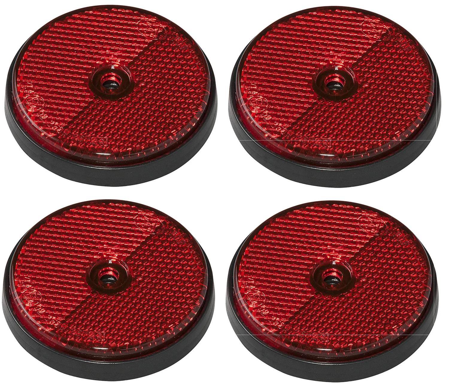 Vier runde rote reflektierende Scheiben auf schwarzen Sockeln, in einem Quadratmuster angeordnet, zur Sichtbarkeit und Sicherheit verwendet.