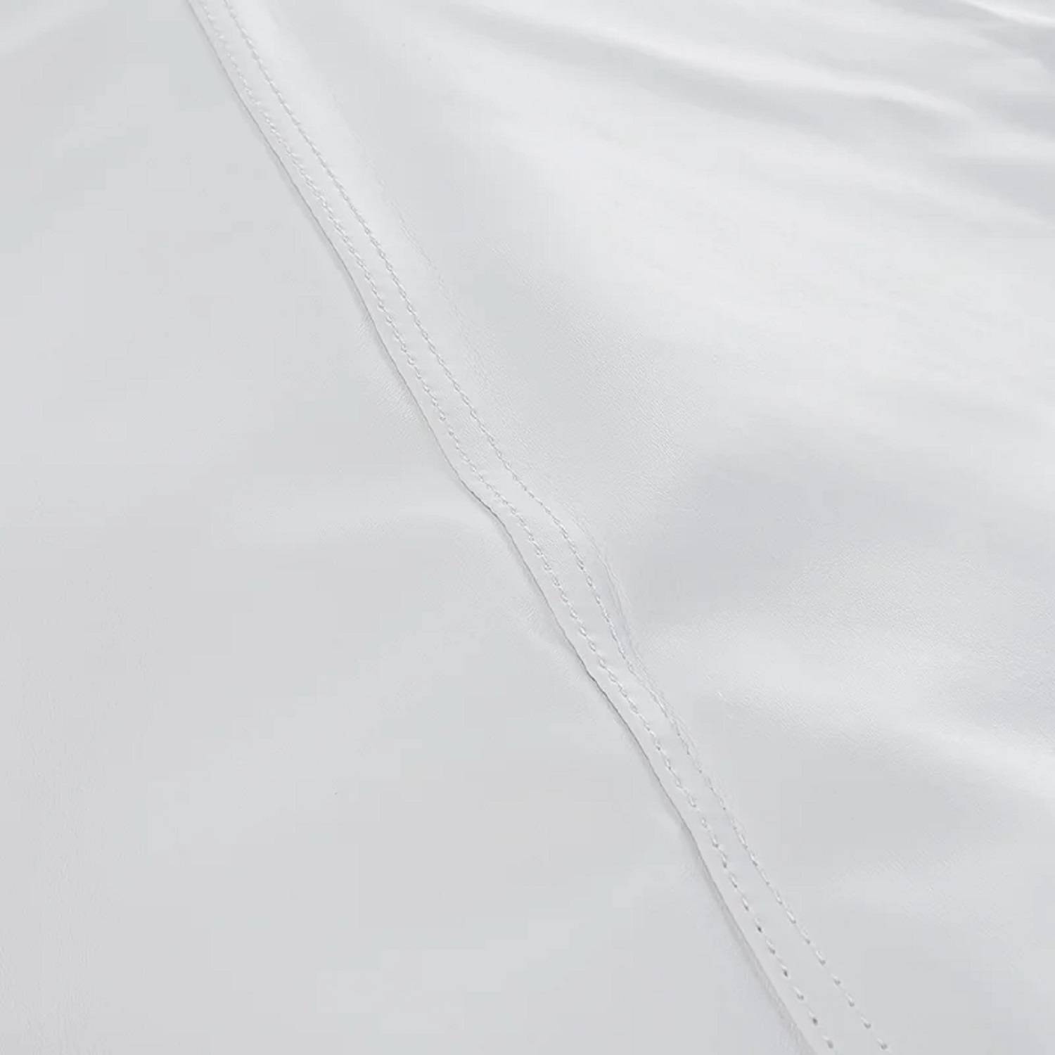 Nahaufnahme einer weißen, gesteppten Oberfläche mit Stickereimitten, die Textur und Stofffalten zeigt.