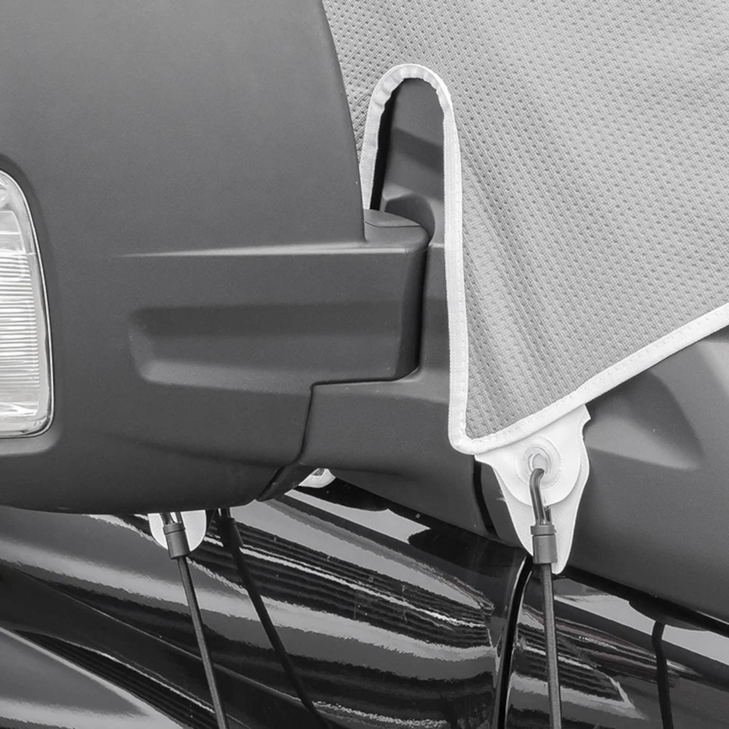 Eine Nahaufnahme des Seitenspiegels und Lenkers eines geparkten Motorrads, mit einem grauen Schutzstoff bedeckt.