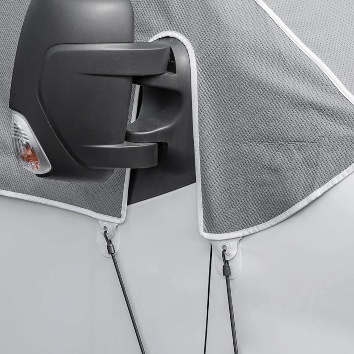 Seitenspiegel eines Fahrzeugs, der mit einem grauen Schutzblatt abgedeckt ist, das durch Riemen befestigt wird.