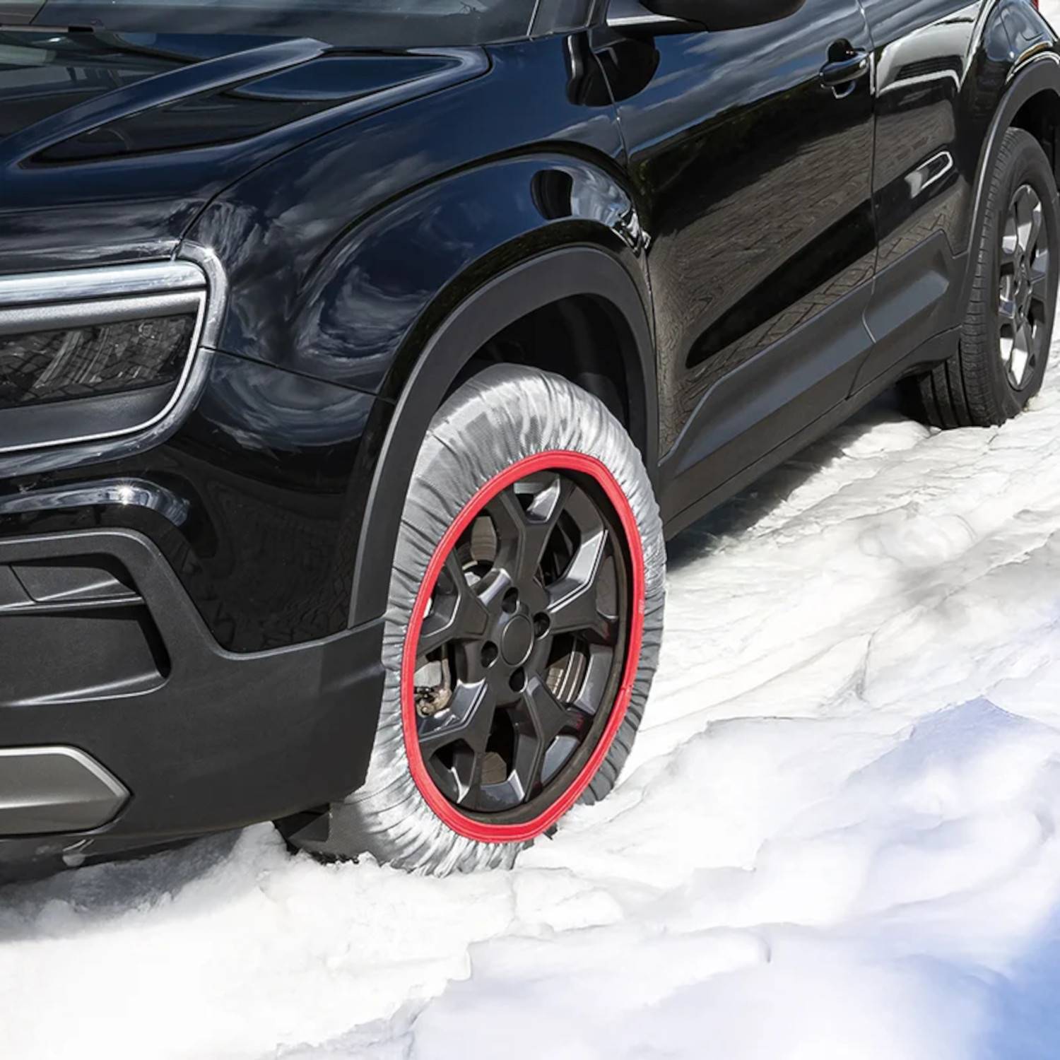 Ein schwarzer SUV mit Reifenhüllen fährt durch Schnee und demonstriert Traktion und Winterbereitschaft.