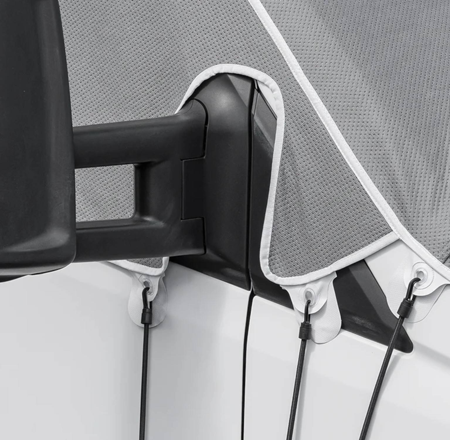 Nahaufnahme von magnetischen Bootshüllenbefestigungsriemen mit Haken, die über den Bootsrand gespannt sind. Der Stoff wirkt robust und ist eng am Bootsrand anliegend.