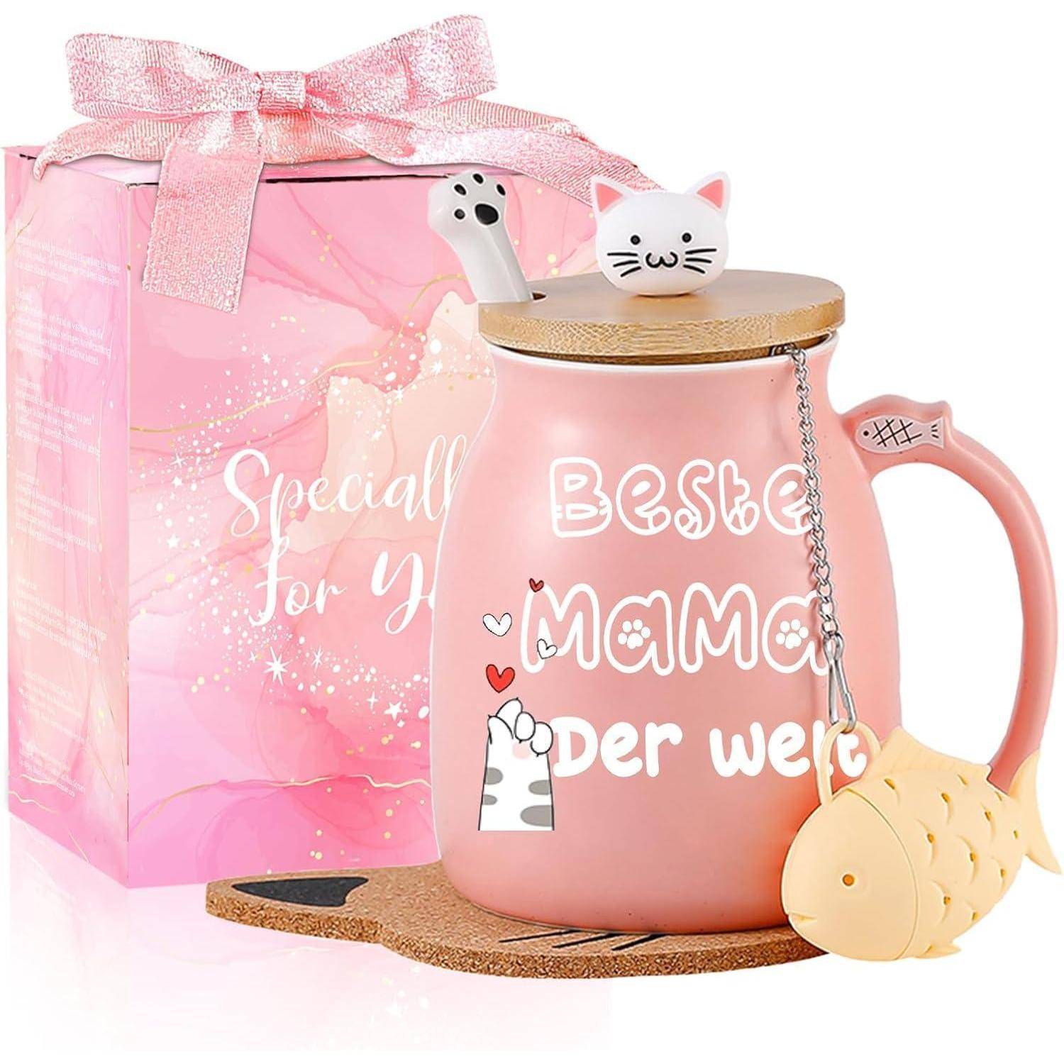 Eine rosa Tasse mit der Aufschrift 'Beste Mama der Welt' neben einer passenden Geschenkbox. Die Tasse zeigt ein Katzendesign und einen fischförmigen Teesieb.
