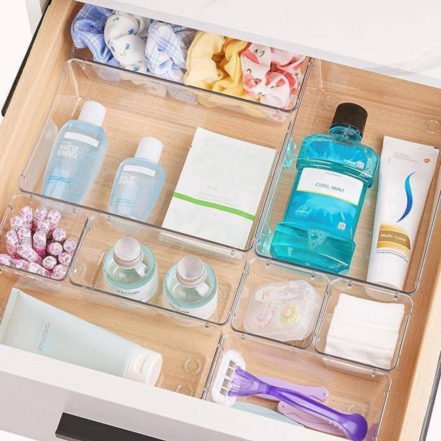 Eine organisierte Schublade mit Hygieneartikeln: Mundwasser, Lotionen, Rasierer, Feuchttücher, Wattestäbchen und Zahnbürsten, in klare Abschnitte sortiert.