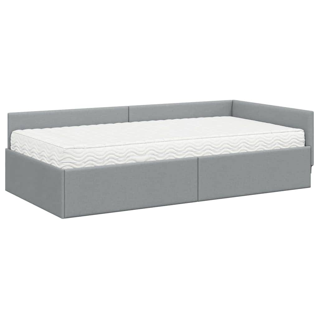 Ein graues gepolstertes Tagesbett mit weißer Matratze, mit minimalistischem Design und zwei Unterbett-Schubladen zum Verstauen, geeignet für kleine Räume.
