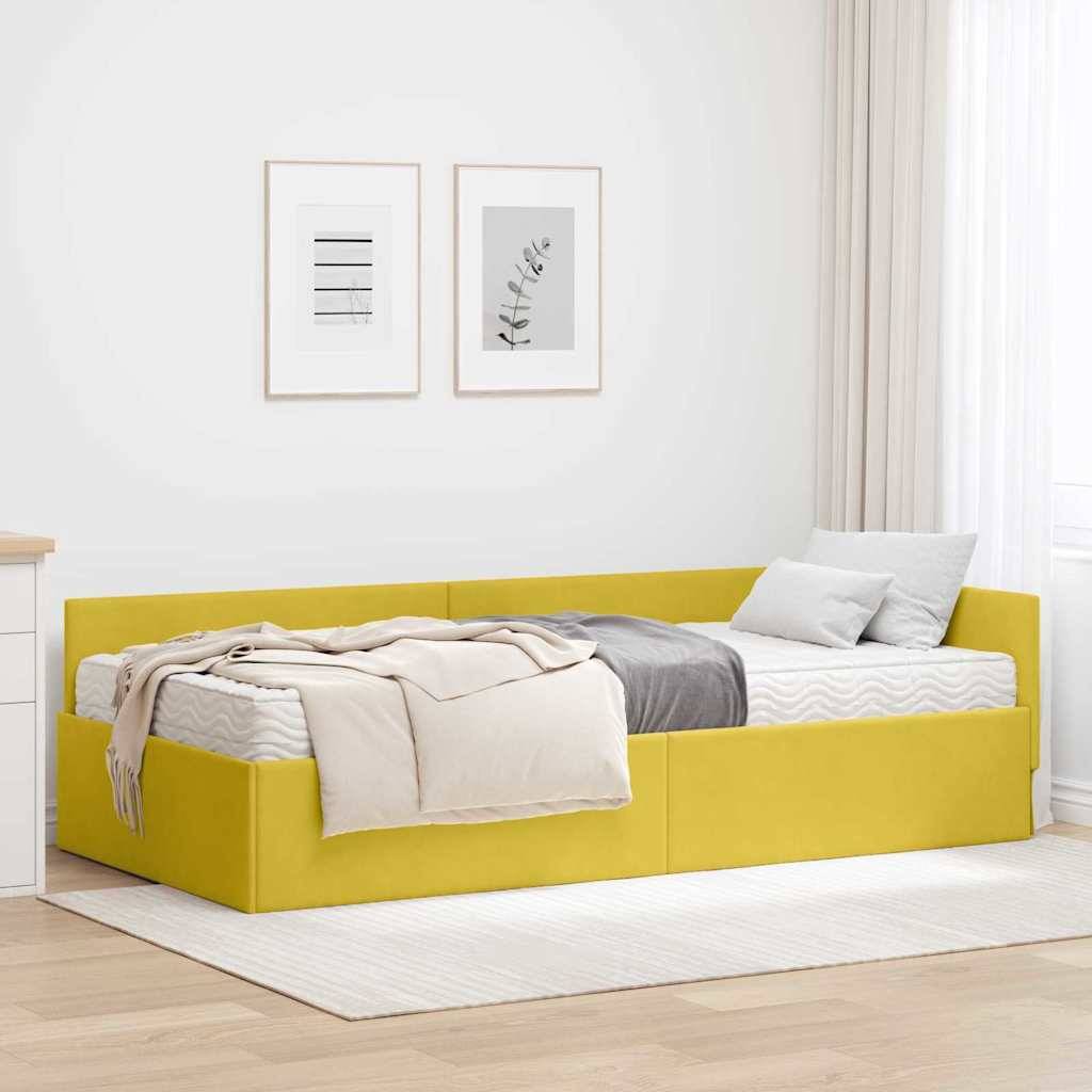 Ein gemütliches Zimmer mit einem gelben Bett, einer beige Decke und grauen Kissen. Zwei gerahmte Kunstwerke an der Wand darüber, Licht, das durch die Vorhänge fließt.