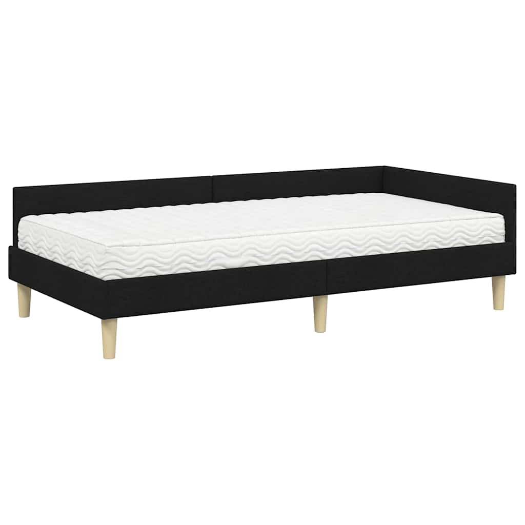 Ein schwarzes Tagesbett mit Holzbeinen und einer weißen Matratze, von der Seite betrachtet.