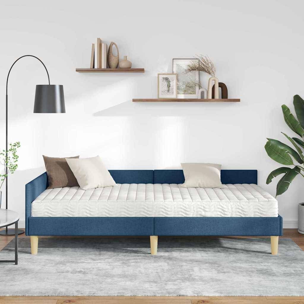 Ein modernes Wohnzimmer zeigt ein blaues Schlafsofa mit beige und braunen Kissen, eine Stehlampe, freischwebende Regale mit Deko und eine Topfpflanze.