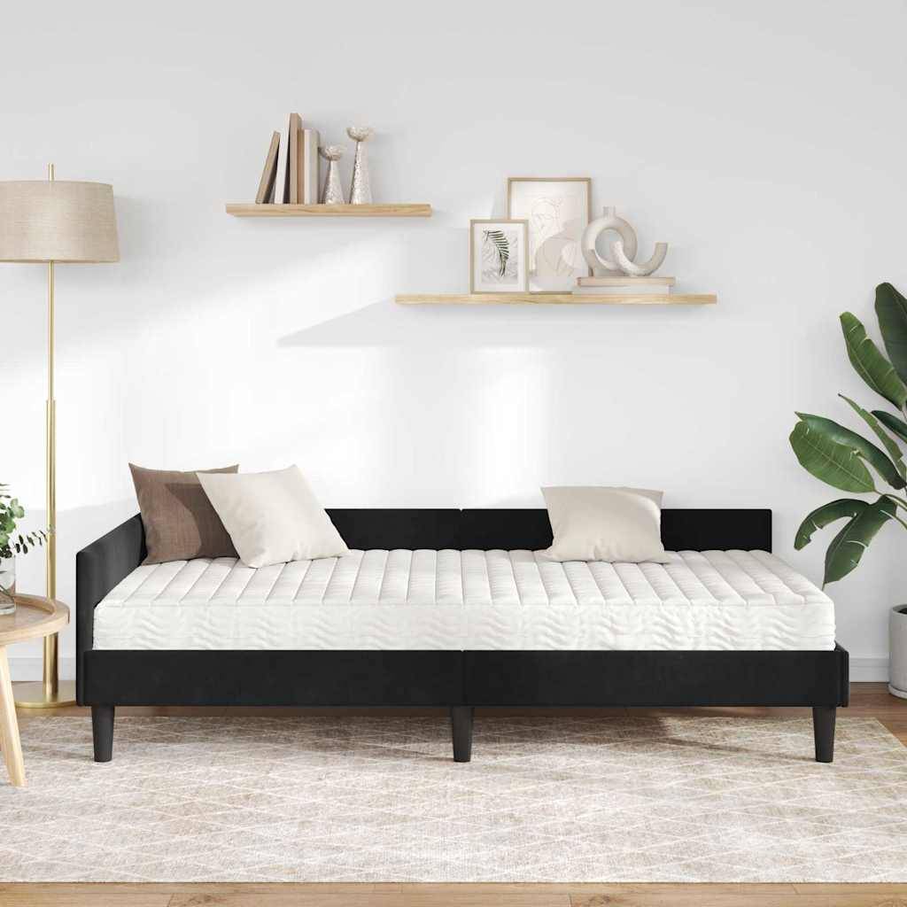 Ein modernes Wohnzimmer mit einem schwarzen Tagesbett mit weißen Kissen, flankiert von Kissen. Die minimalistische Einrichtung umfasst Regale mit Kunst und Büchern.