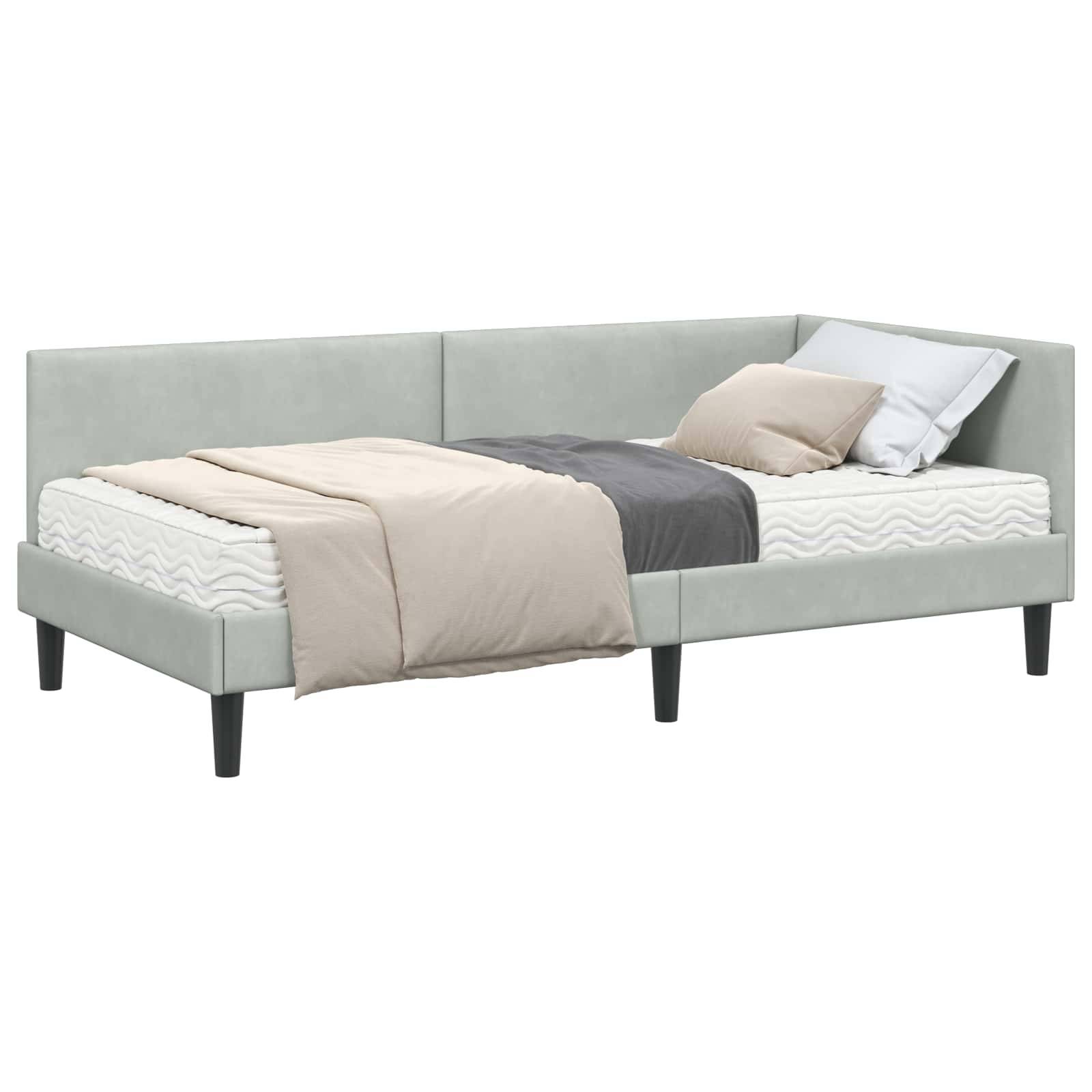 Ein modernes L-förmiges Eckbett mit einem hellgrauen Kopfteil und Fußteil, zwei Kissen und einer beige-grauen Decke oben drauf.