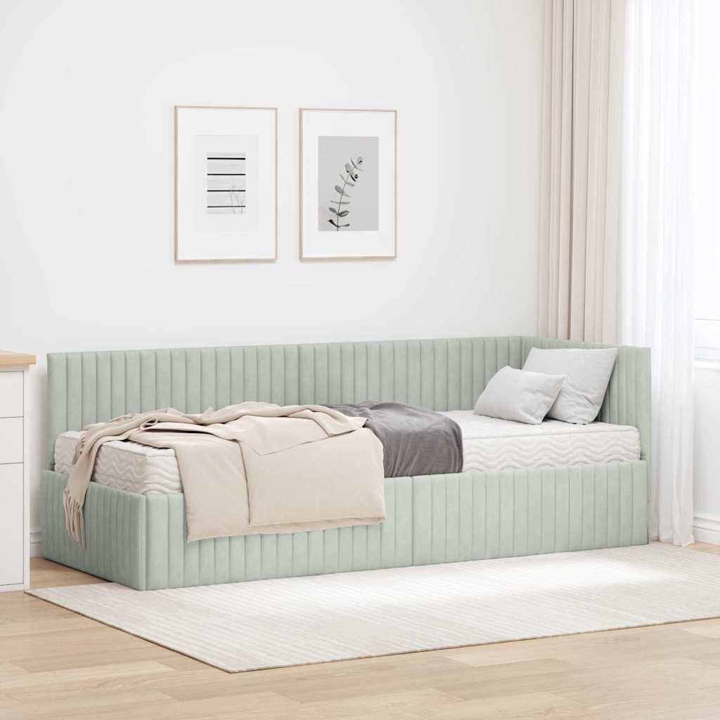 Ein minimalistisches Schlafzimmer mit einem hellgrünen Tagesbett, beigen und grauen Decken und weißen Kissen. Zwei gerahmte Kunstwerke hängen über dem Bett.