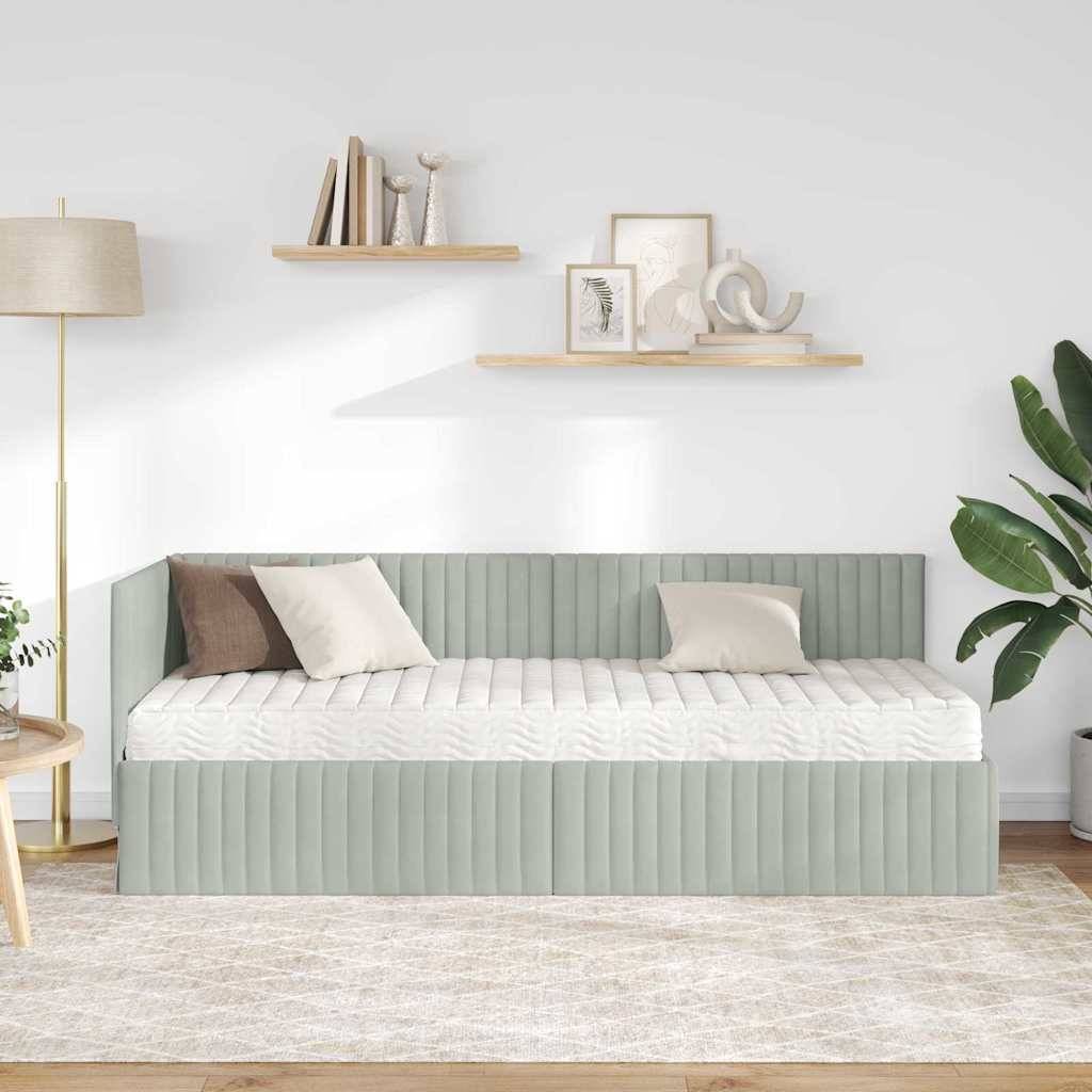 Ein minimalistisches Wohnzimmer zeigt ein graues Tagesbett mit beigen und weißen Kissen, eine Stehlampe, zwei Holzregale mit Dekorationsstücken und eine grüne Pflanze.