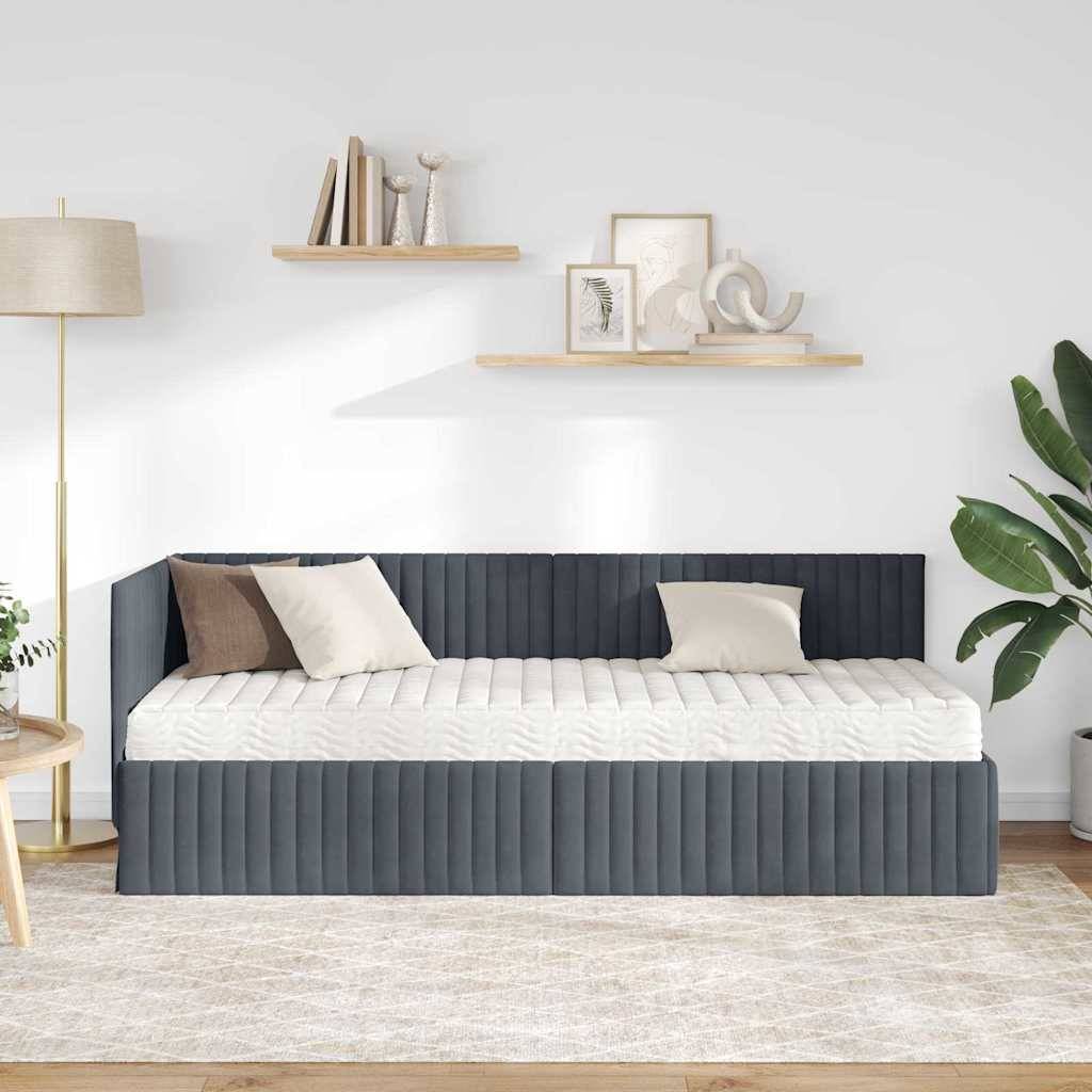 Eine gemütliche Wohnzimmergestaltung mit einem grauen Tagesbett mit weißen Kissen, einer Lampe, einer Pflanze und minimalistischen Regalen mit Dekoration darüber.