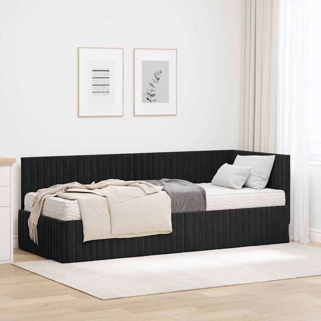 Ein minimalistisches Schlafzimmer verfügt über ein schwarzes Tagesbett mit grauer und beigefarbener Bettwäsche, eine weiße Kommode und gerahmte botanische Drucke an einer weißen Wand.
