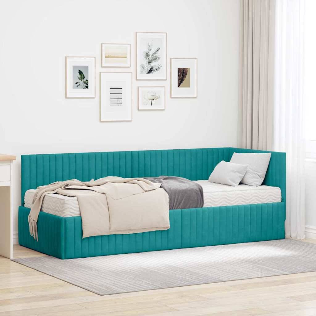 Ein türkisfarbenes Tagesbett mit einer beigen Decke und zwei weißen Kissen steht neben einem Schreibtisch; sechs gerahmte Kunstwerke hängen an der Wand darüber.