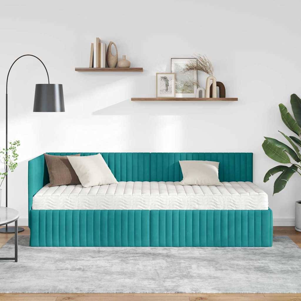 Ein modernes Schlafzimmer mit einem blaugrünen Tagesbett, weißen und beigen Kissen und einer Stehleuchte. Regale mit Dekoration sind an einer weißen Wand montiert.