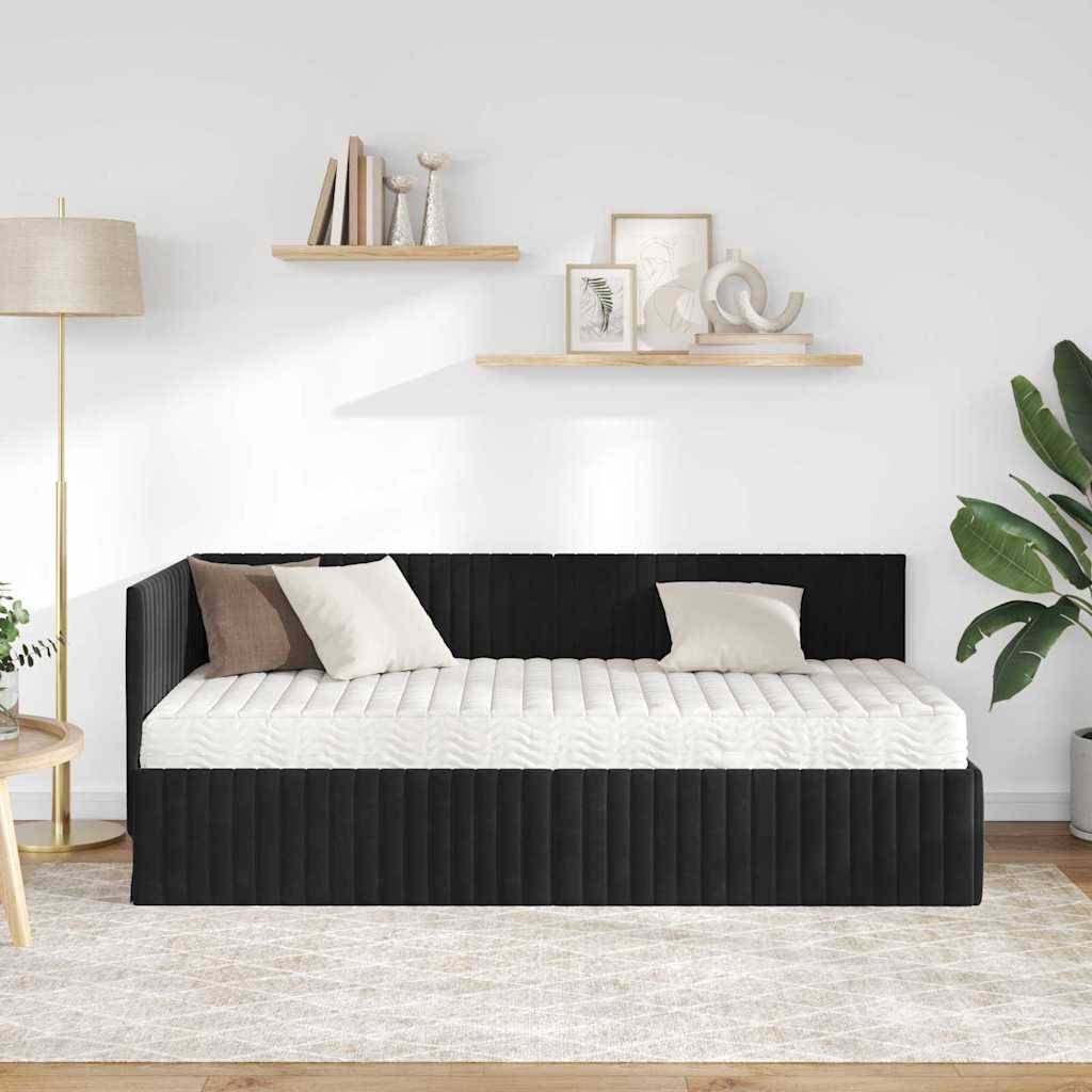 Ein modernes Wohnzimmer zeigt ein schwarzweißes Tagesbett mit zwei Kissen, einen gestreiften Teppich, eine hohe Lampe und Regale mit Dekorationselementen und einer Pflanze.