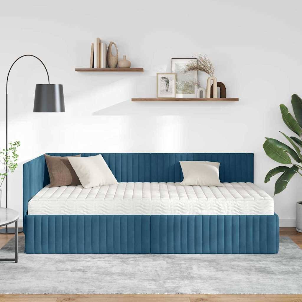 Ein modernes Wohnzimmer mit einem blauen Samtsofa, weißen Kissen und einem neutralen Teppich. Regale mit Dekoration und eine hohe Lampe verleihen Stil.