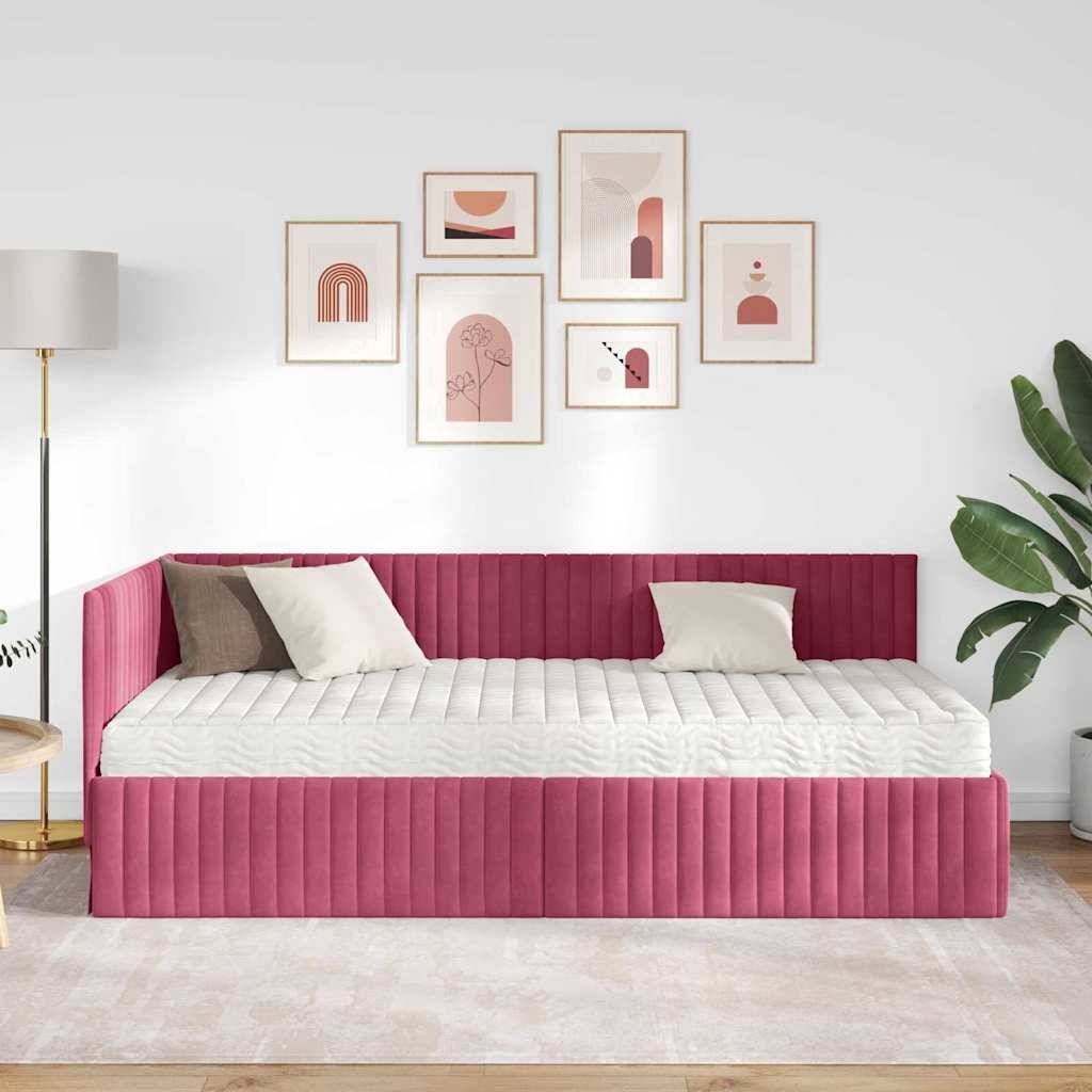 Ein moderner Raum zeigt ein Tagesbett in Magenta mit weißen und beigen Kissen, eine Galeriewand mit abstrakter Kunst, eine Topfpflanze und eine Stehlampe.