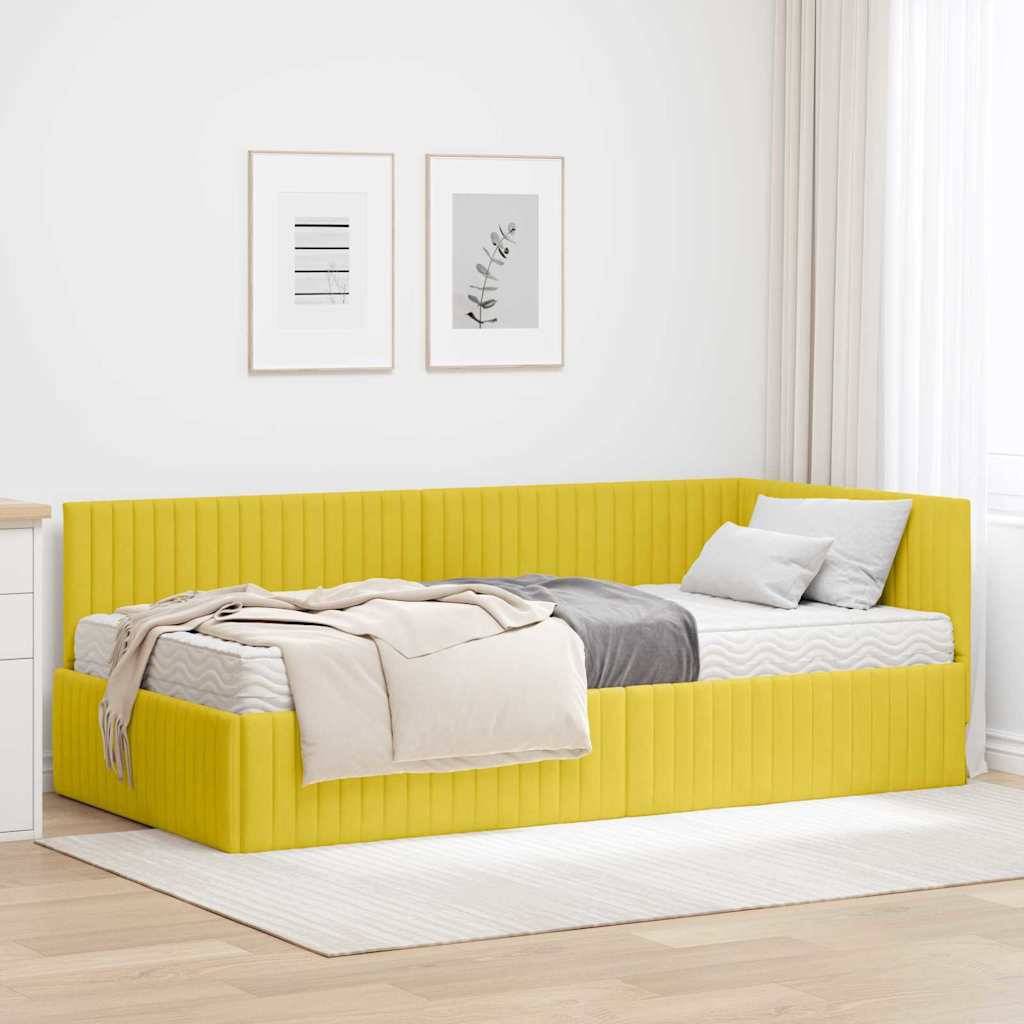 Ein gelbes Tagesbett mit einer beigen Decke und einem grauen Kissen steht an einer weißen Wand, an der zwei gerahmte Kunstwerke hängen.