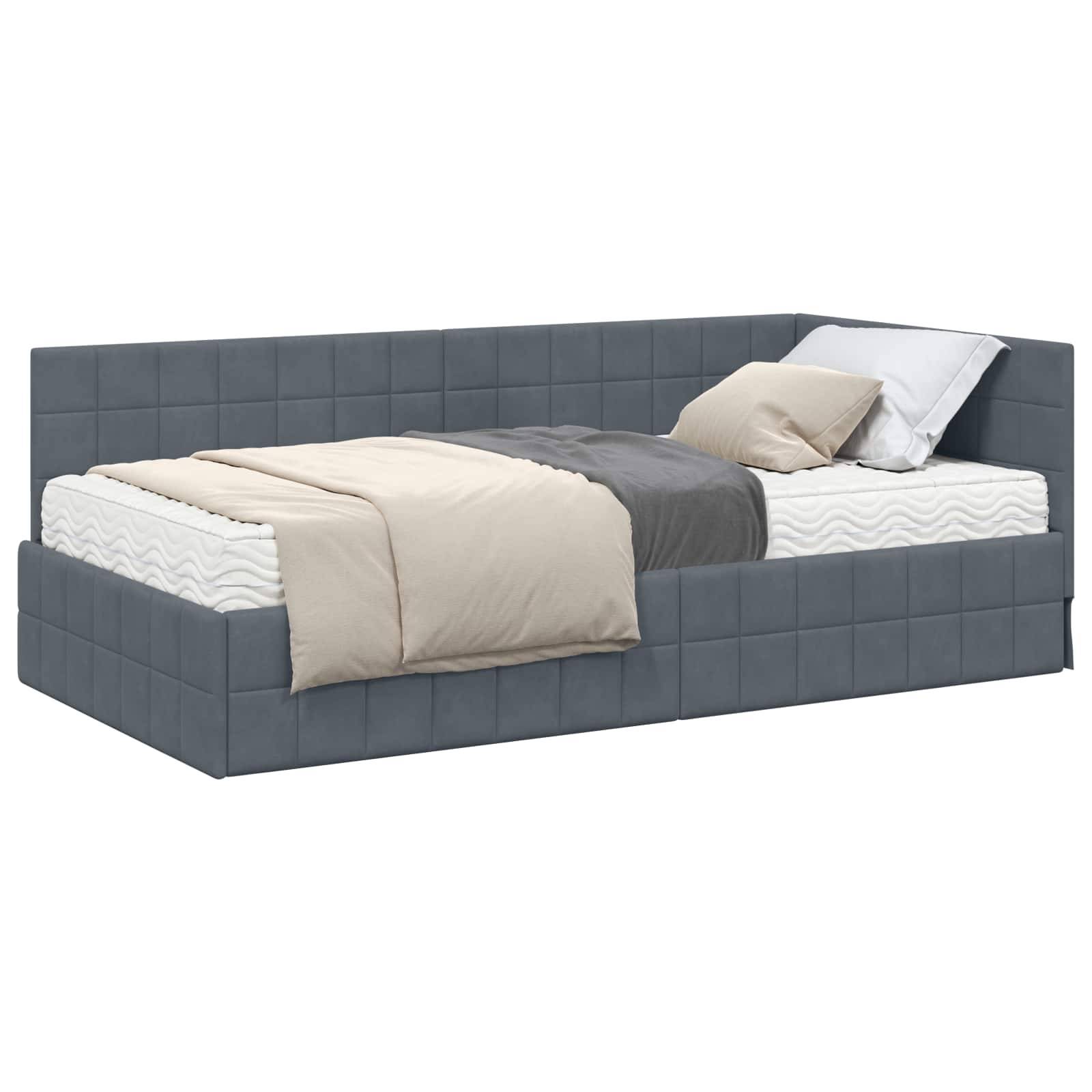 Ein blauer, gepolsterter Tagesbett mit Steppdeckenmuster, weißer Matratze, grauen und beigen Decken und zwei Kissen, von links aus gesehen unter einem Winkel.