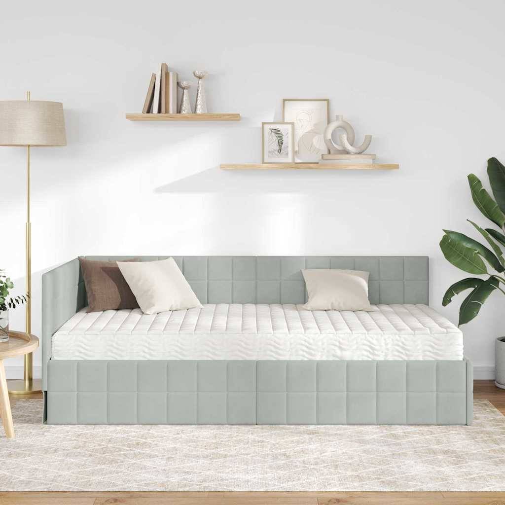Ein modernes Wohnzimmer mit einem hellgrau gepolsterten Tagesbett, weiß- und beigefarben Kissen, einer Stehlampe, hölzernen Regalen mit Dekoration und einer Pflanze.