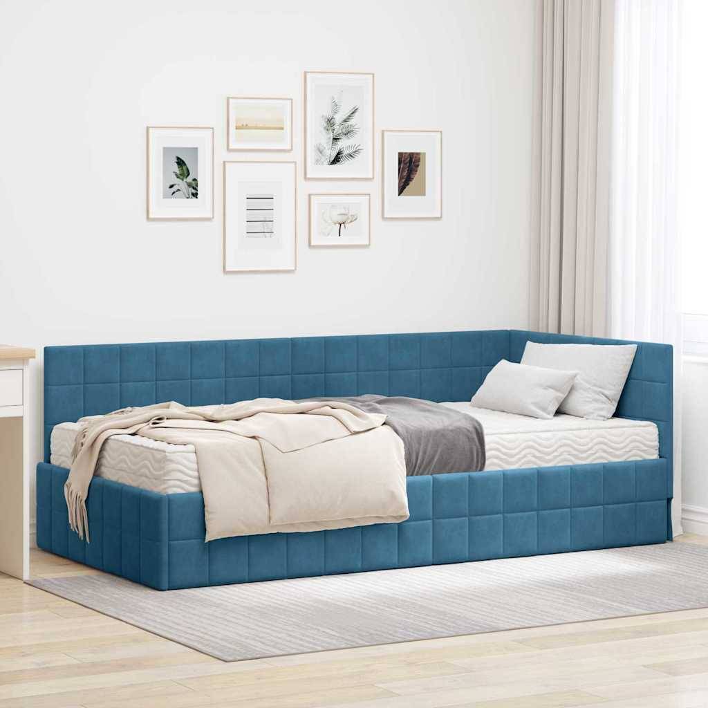 Ein modernes Schlafzimmer mit einem blau gepolsterten Tagesbett mit beigem Überwurf und Kissen, weißen Wänden, die mit gerahmten Kunstdrucken geschmückt sind, und einem hellem Holzboden.