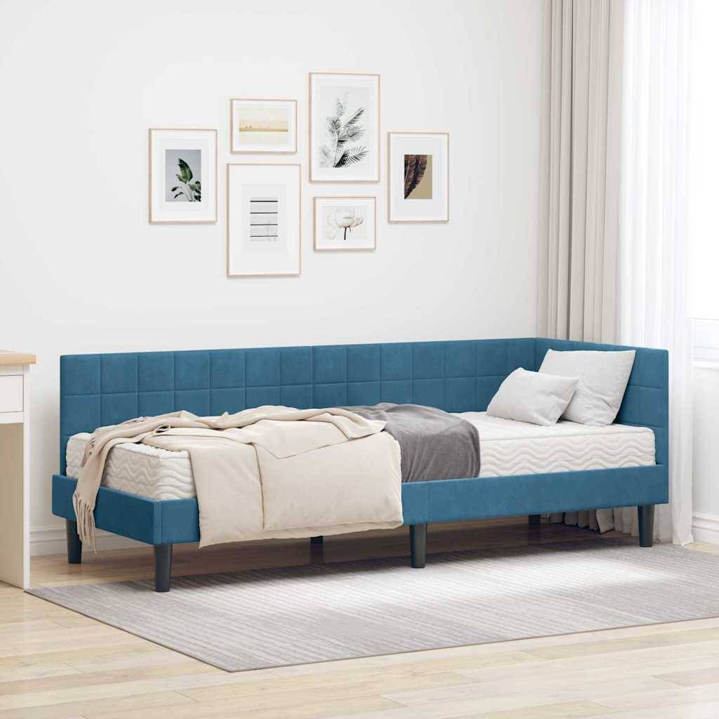 Ein modernes Schlafzimmer präsentiert eine blau gepolsterte Tagesbettstelle mit grau und beige gehaltener Bettwäsche, in der Nähe eines weißen Schreibtischs und einer mit Kunstwerken geschmückten Wand.
