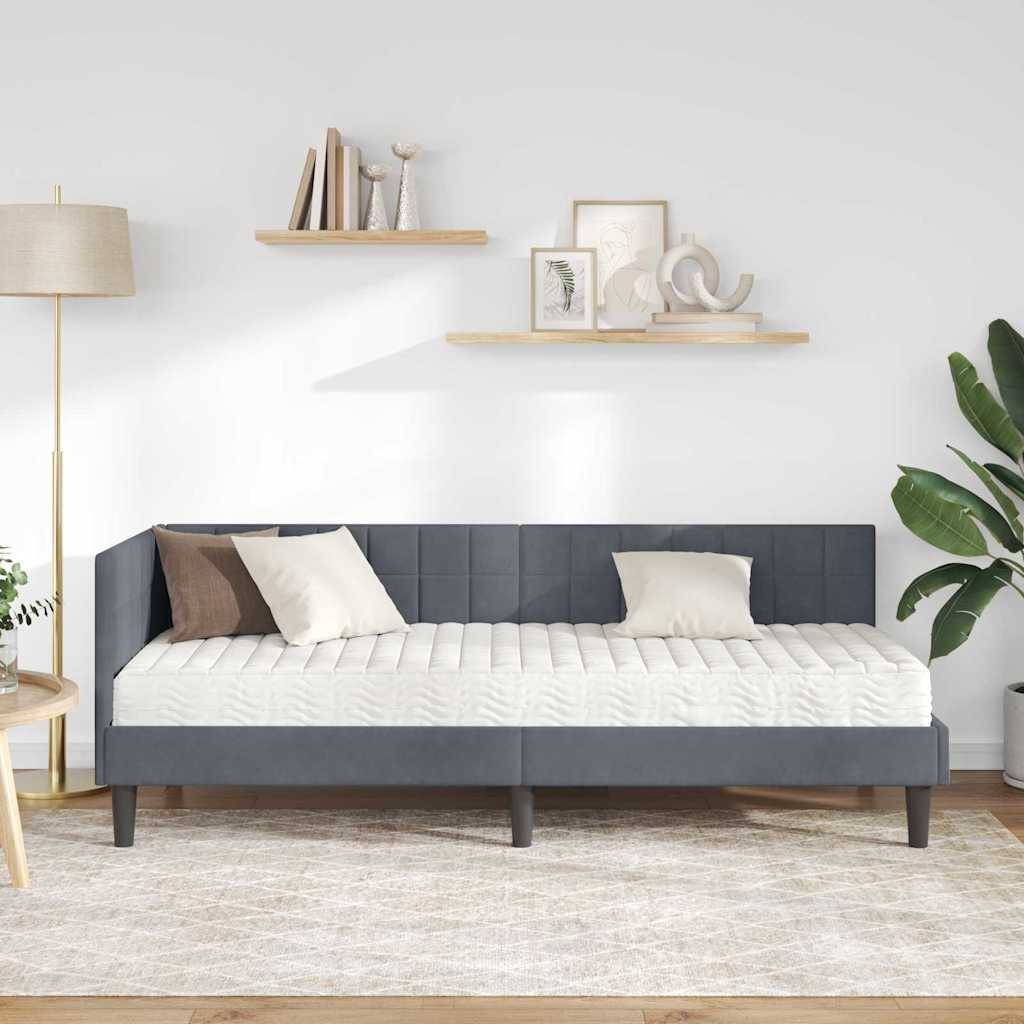 Moderner Wohnraum mit einer eleganten grauen Tagesliege, beigen Kissen und einer großen Zimmerpflanze. Regale mit Dekorationsstücken und einer Stehlampe.